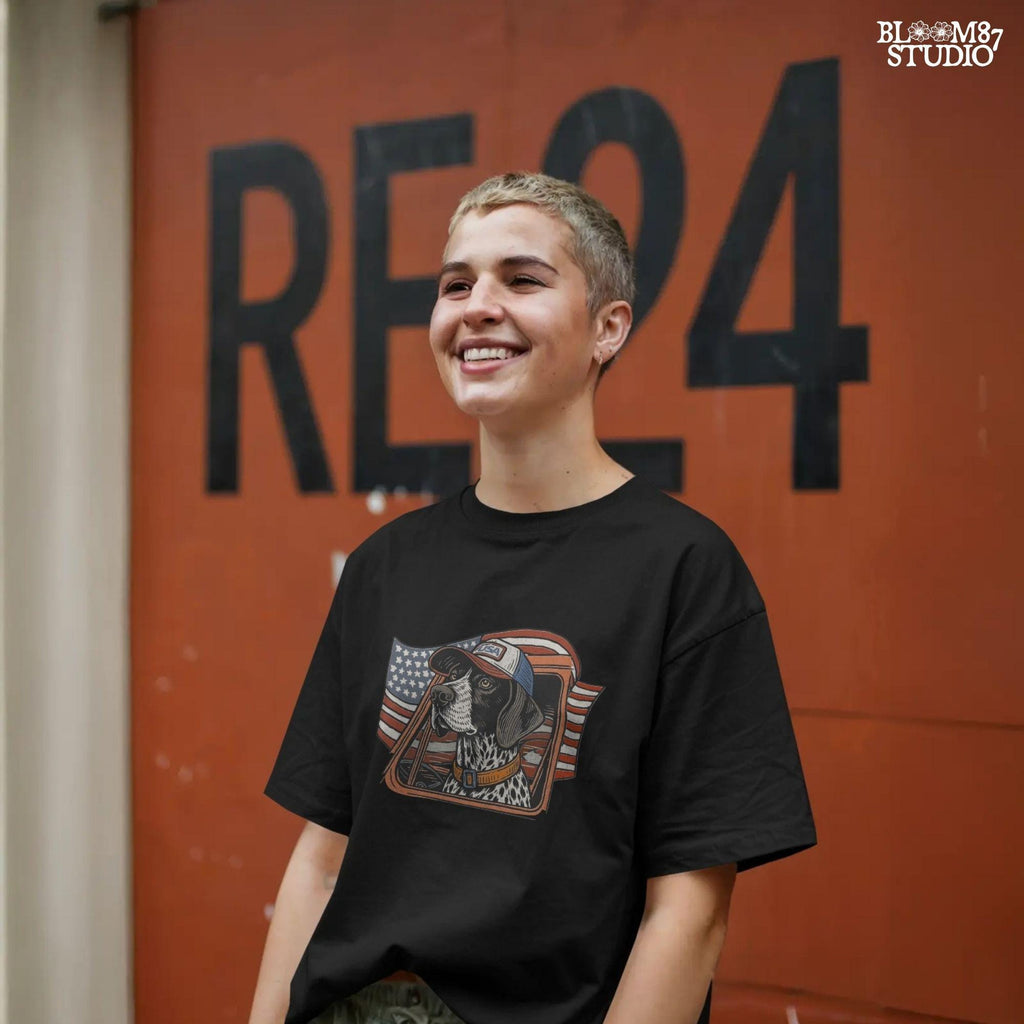 German Shorthaired Pointer dog wearing USA hat looking out of truck window with American flag waving in background