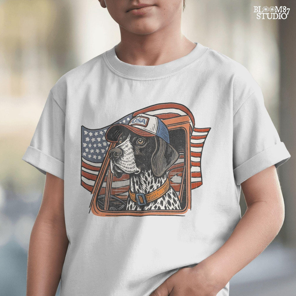 German Shorthaired Pointer dog wearing USA hat looking out of truck window with American flag waving in background