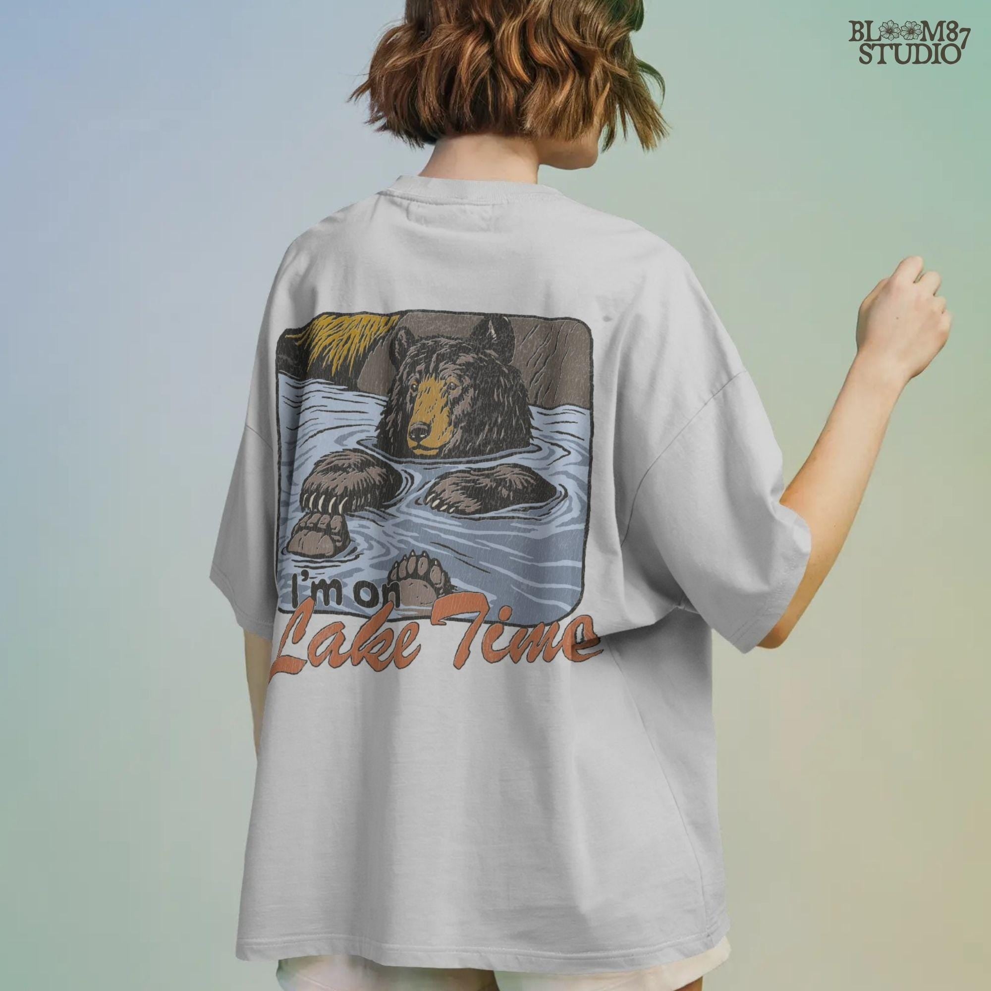 Cartoon bear relaxing in a lake with paws up, text reads “I’m on Lake Time,” in a cozy, vintage outdoor style.