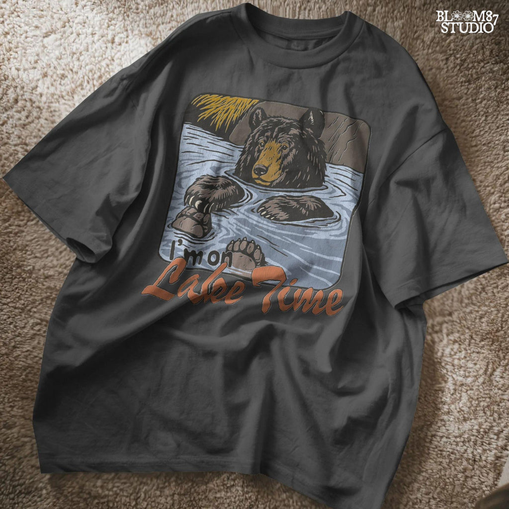 Cartoon bear relaxing in a lake with paws up, text reads “I’m on Lake Time,” in a cozy, vintage outdoor style.