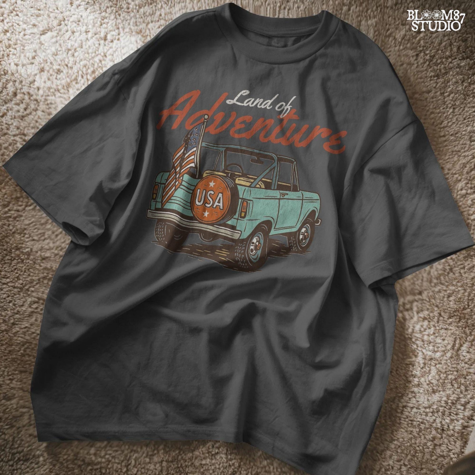 Vintage convertible truck with “USA” spare tire and American flag, text reads “Land of Adventure,” in a retro patriotic illustration style.