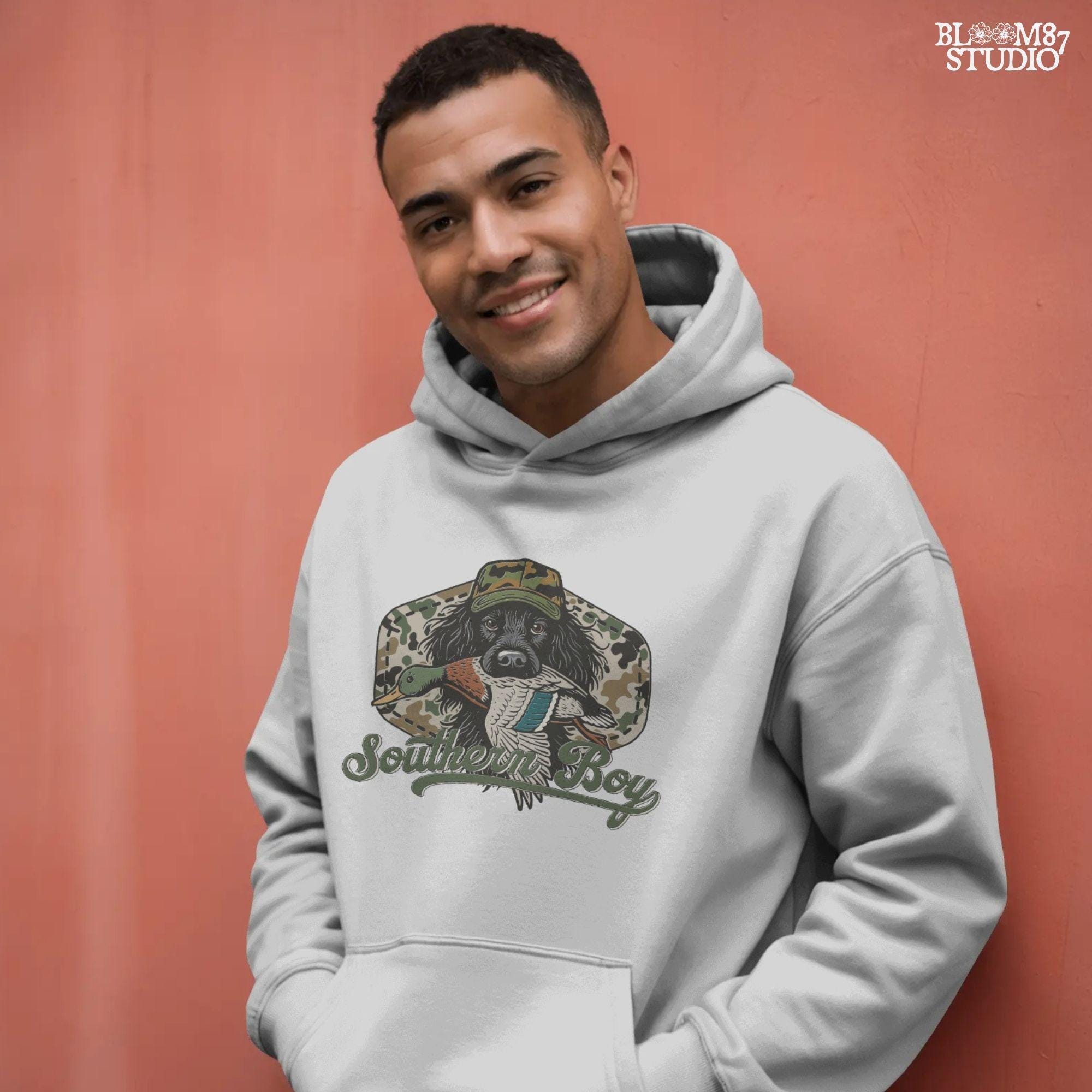 Illustration of a black hunting dog wearing a camo hat, holding a mallard duck in its mouth with the text “Southern Boy” below, in a rustic Southern style.