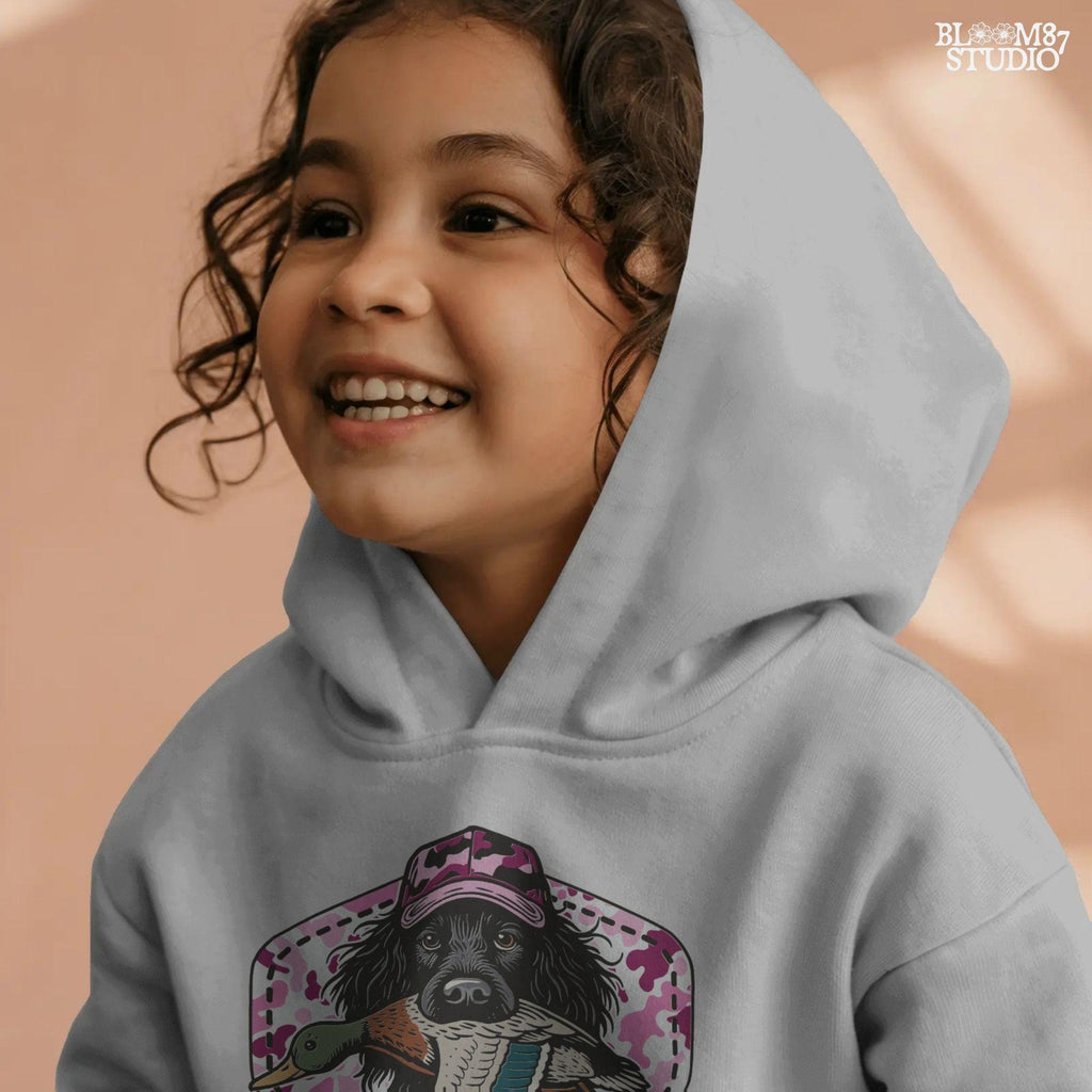 Illustration of a black hunting dog wearing a pink camo hat and holding a mallard duck, with “Southern Girl” text and pink camouflage background.