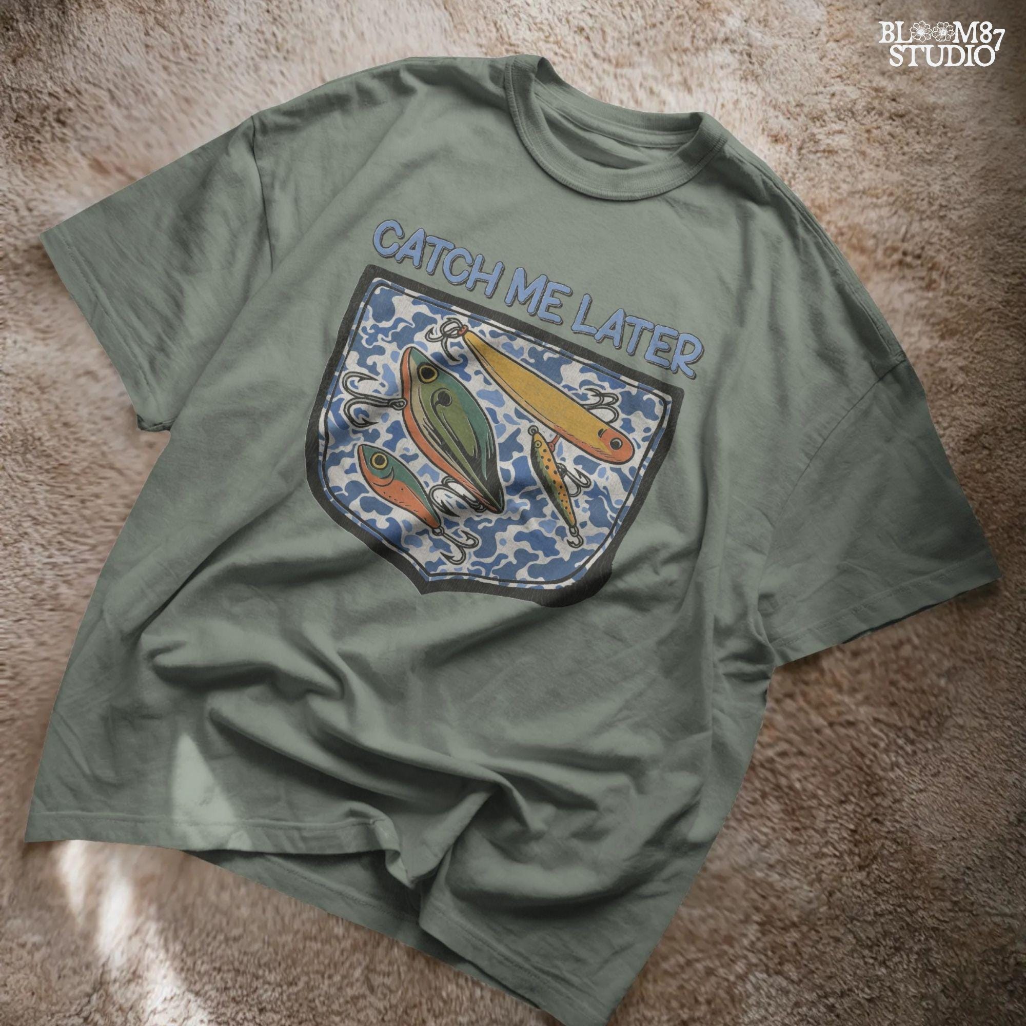 Funny “Catch Me Later” text above a faux blue camo pocket with colorful fishing lures, designed for sublimation printing on fisherman-themed apparel.