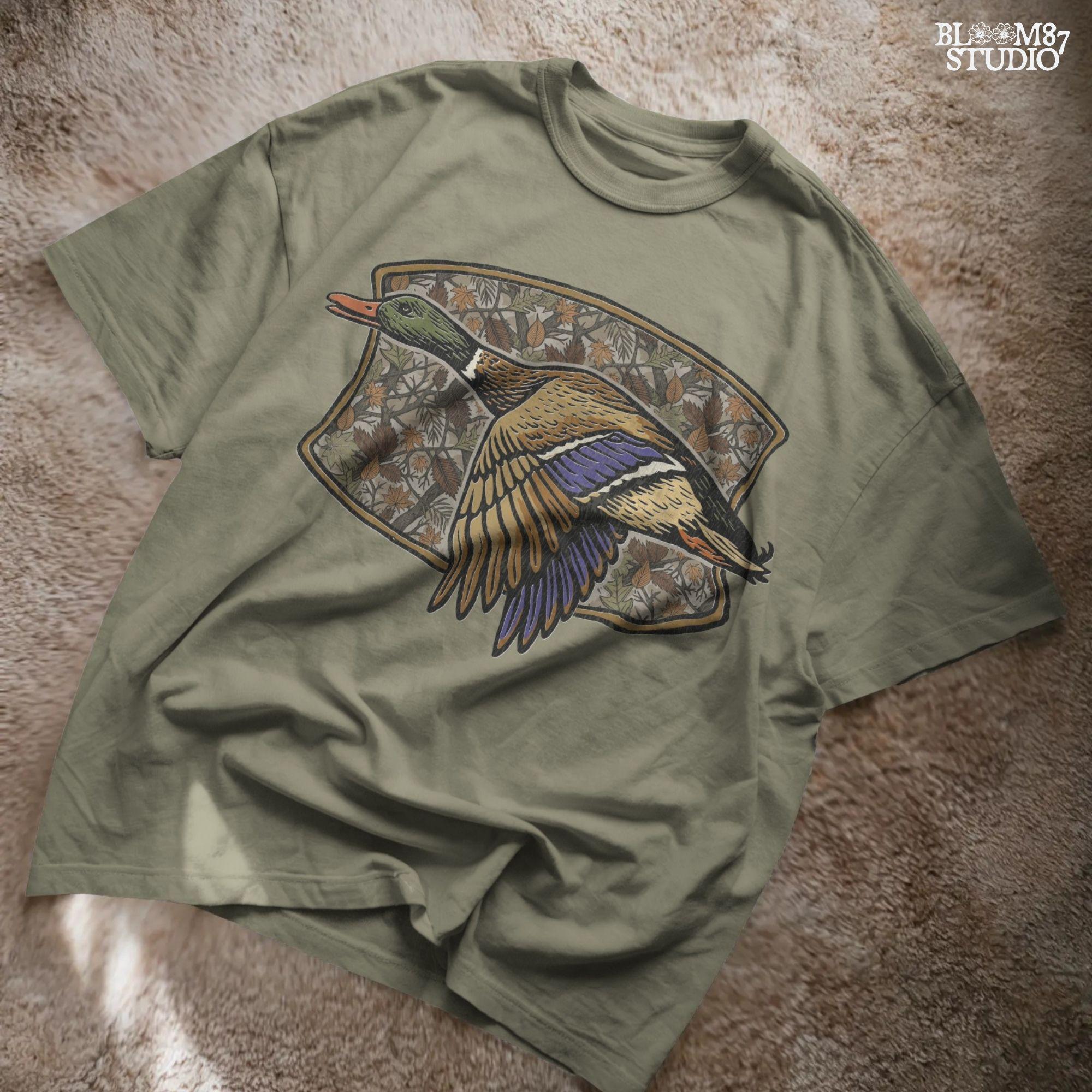 Illustration of a flying mallard duck over a fall camouflage background with oak and maple leaves, designed for hunting-themed sublimation and outdoor shirts.