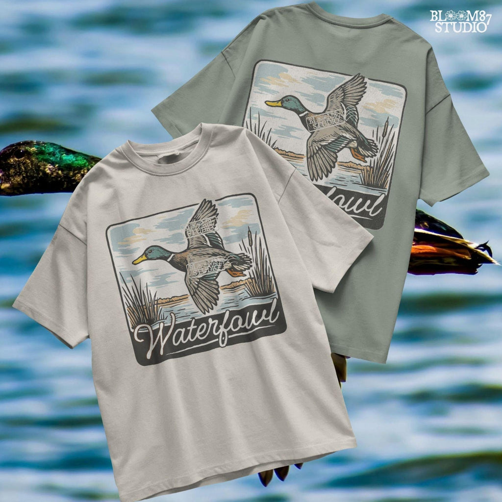 Vintage-style illustration of a flying mallard duck over a marsh with the word “Waterfowl” in script, perfect for duck hunting and outdoor-themed designs.
