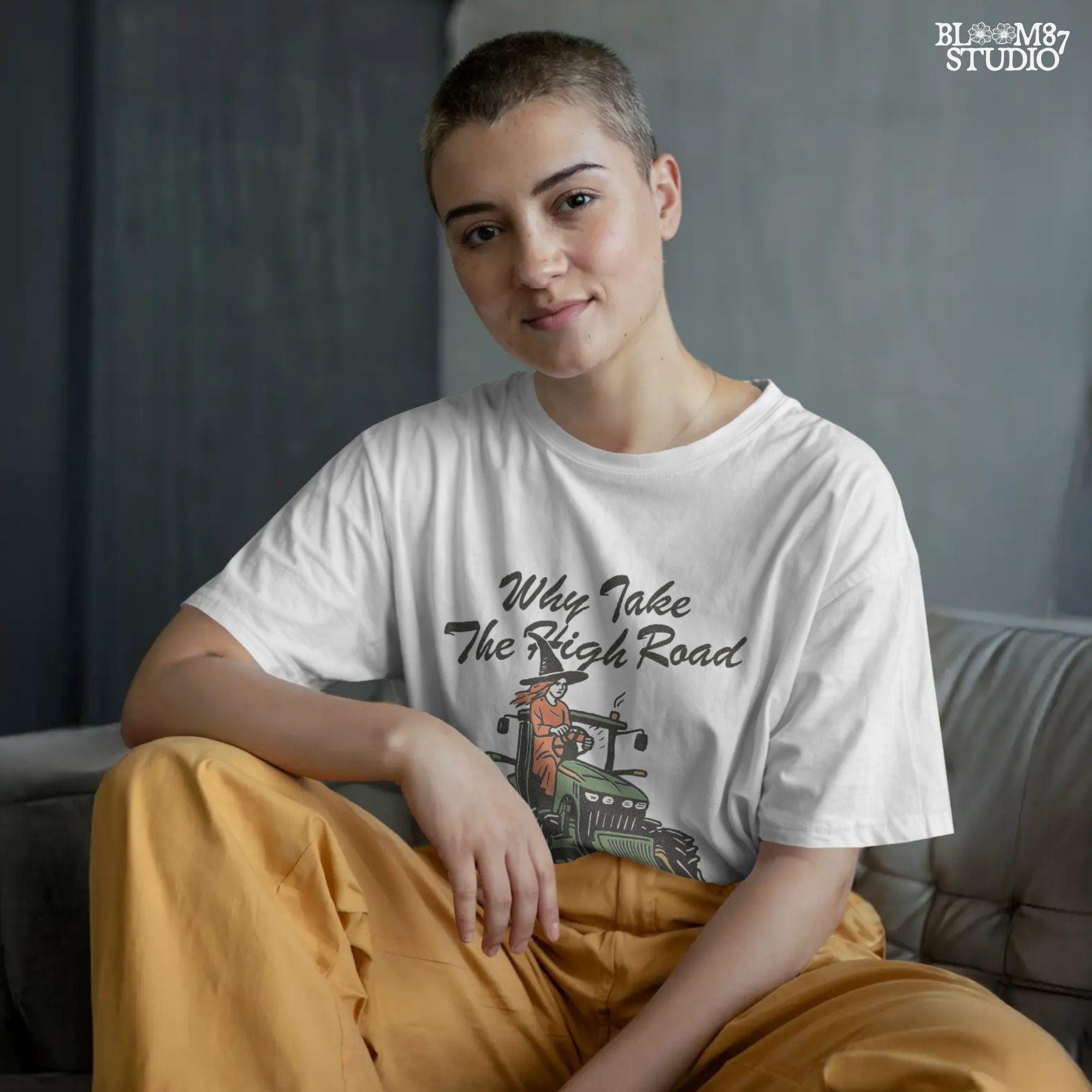 Funny illustration of a red-haired witch in a black hat driving a green tractor with the quote “Why take the high road when you can take the psycho path,” in rustic cartoon style.