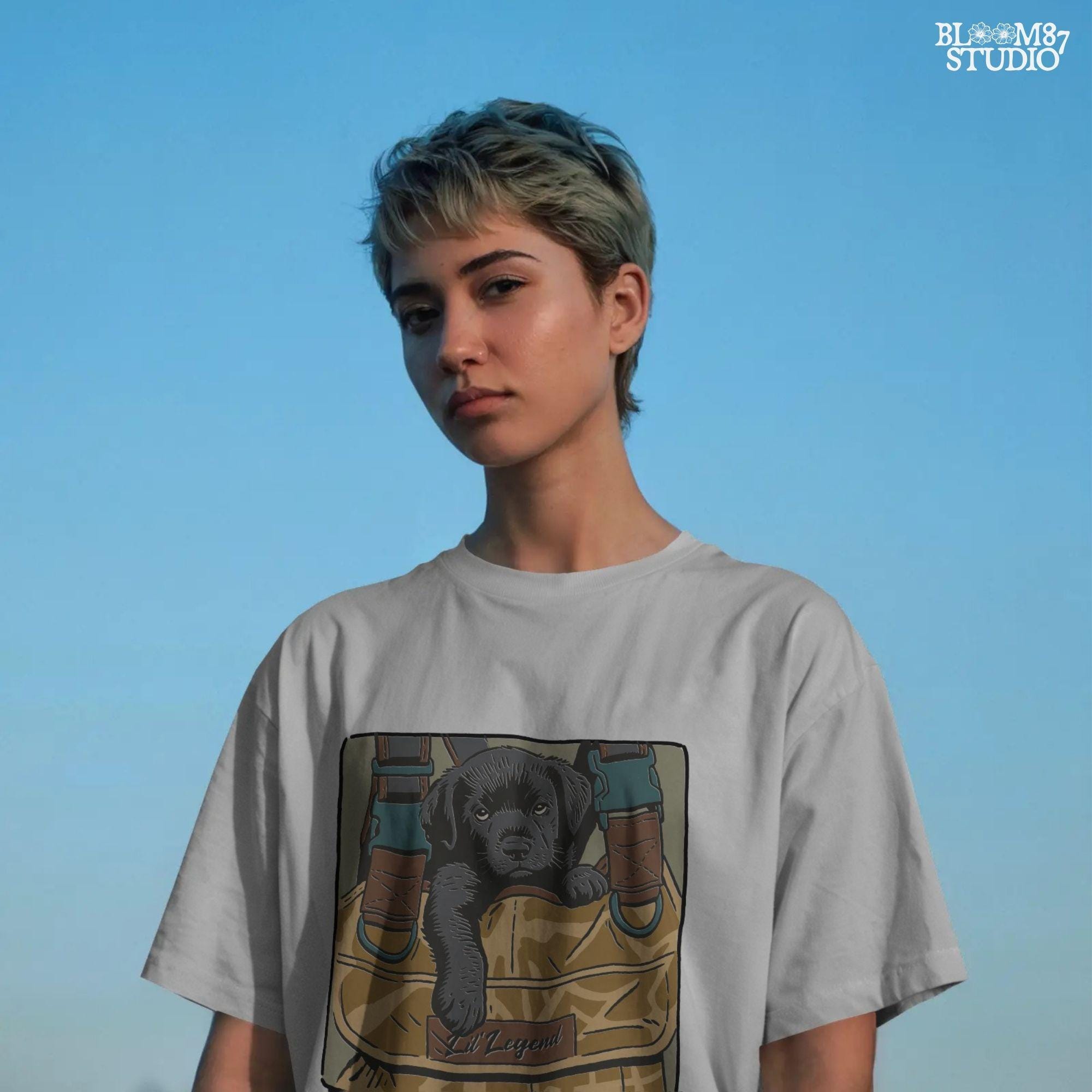 Illustration of a black Labrador puppy resting in a camouflage hunting bag with a “Lil’ Legend” tag – ideal for outdoor-themed sublimation projects.