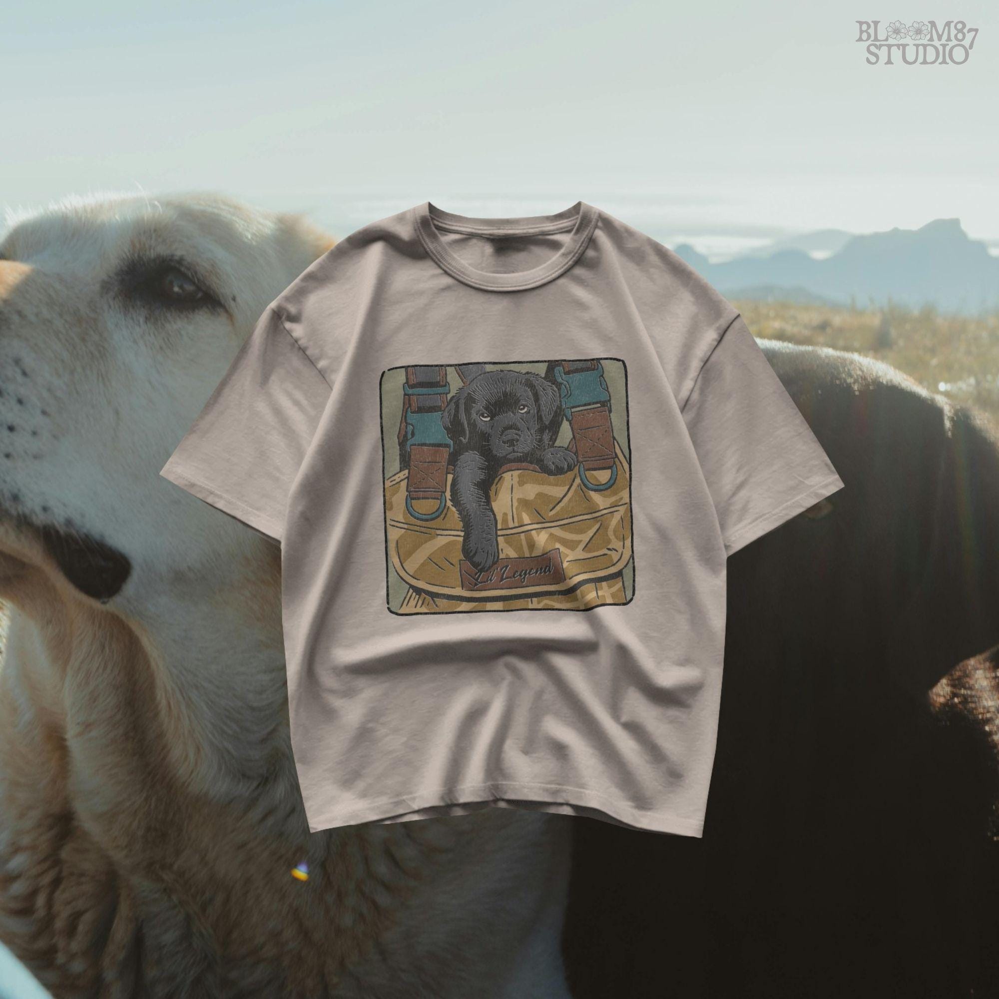 Illustration of a black Labrador puppy resting in a camouflage hunting bag with a “Lil’ Legend” tag – ideal for outdoor-themed sublimation projects.