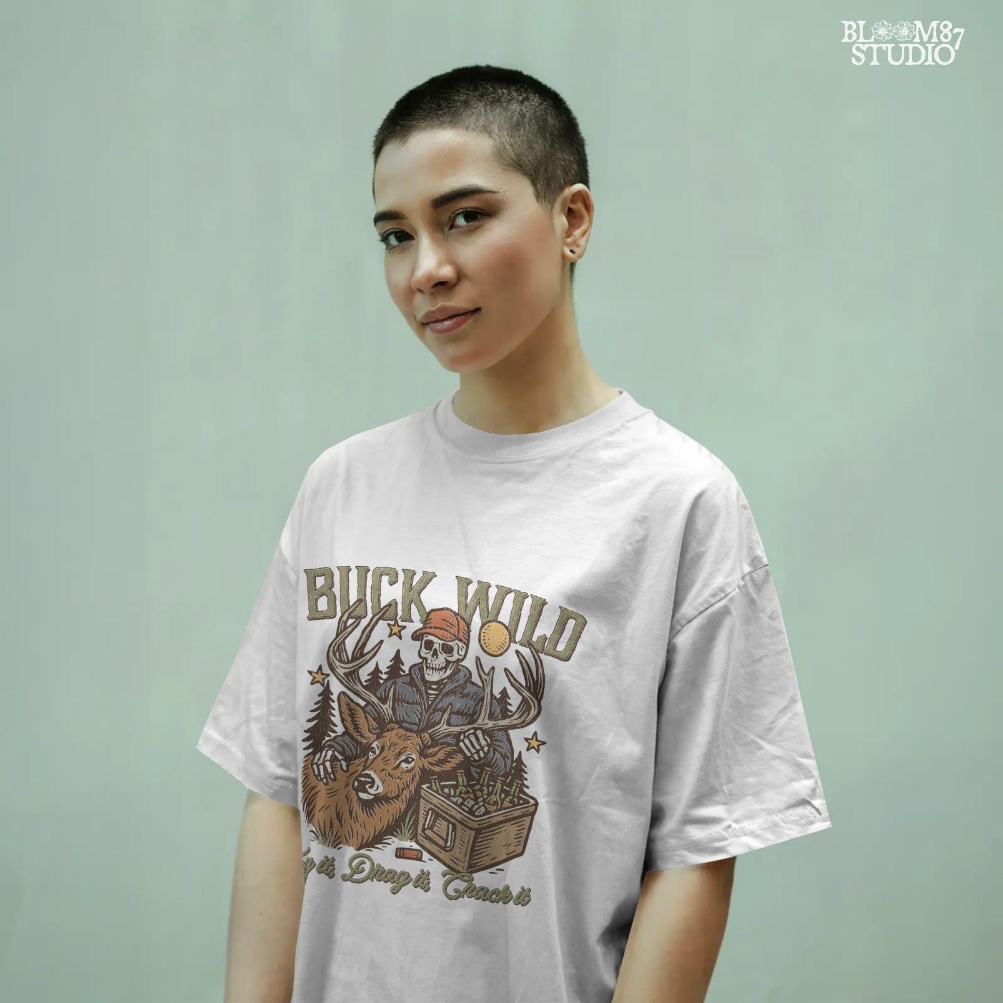 A funny deer hunting illustration with a skeleton hunter holding a buck and cooler of beer under the phrase “Tag it, Drag it, Crack it”.