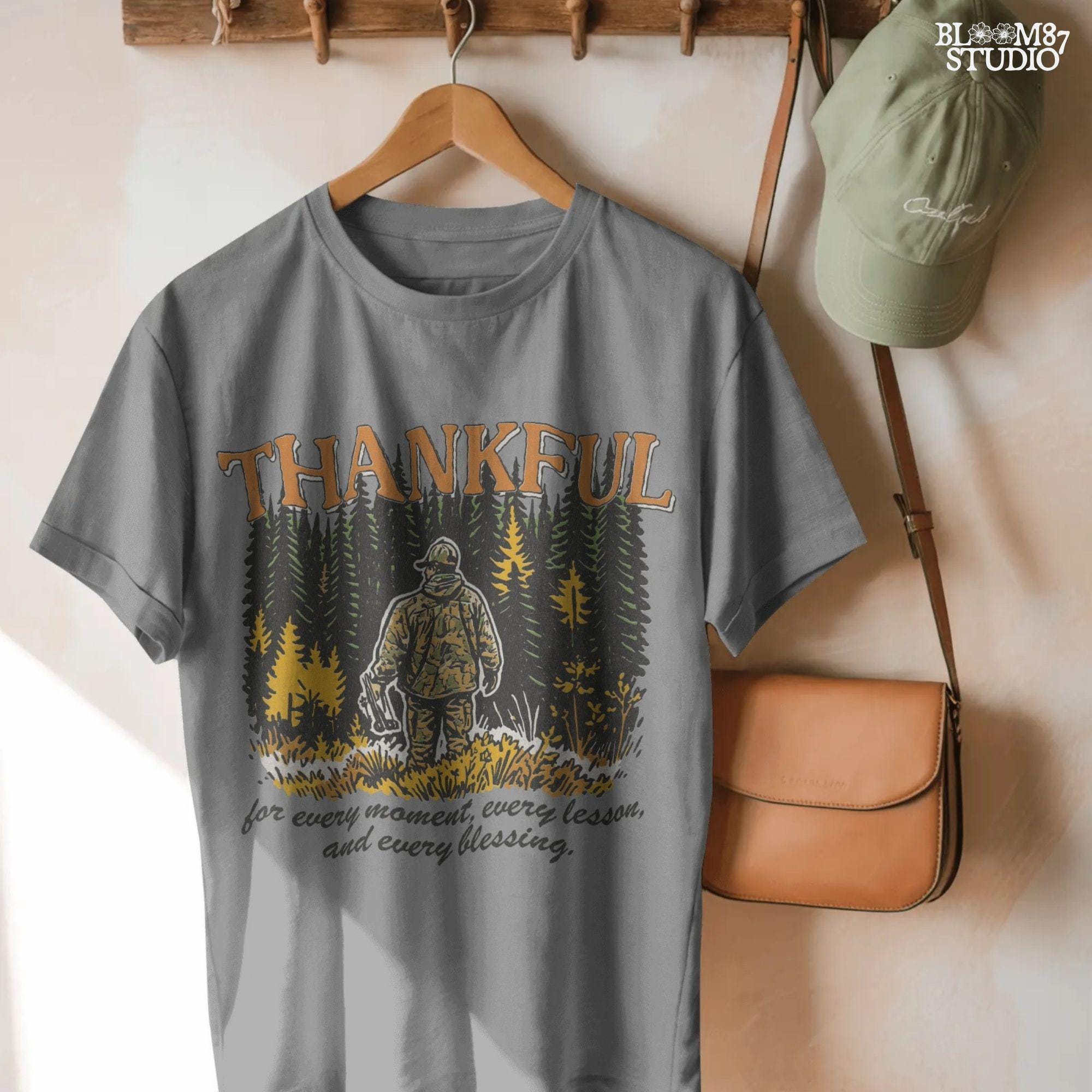 Illustration of a hunter in camo standing in a fall forest with the word “THANKFUL” above and a quote below, designed for sublimation projects.