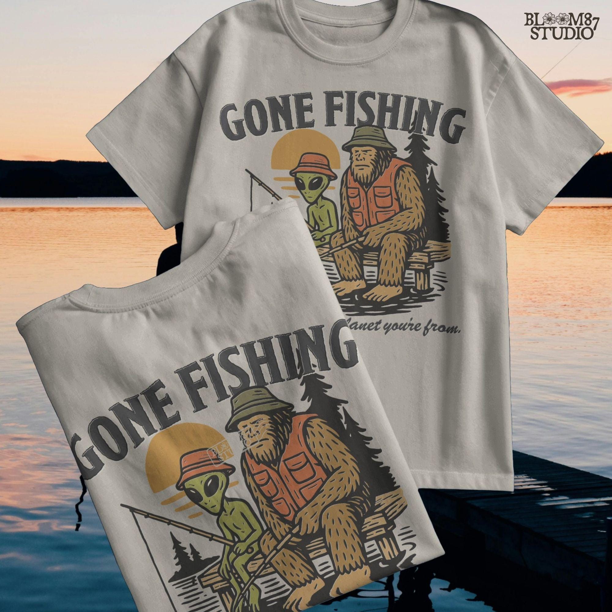 Funny illustration of Bigfoot and an alien fishing together on a lake dock at sunset, wearing fishing hats and vests—perfect for summer and Father’s Day sublimation.