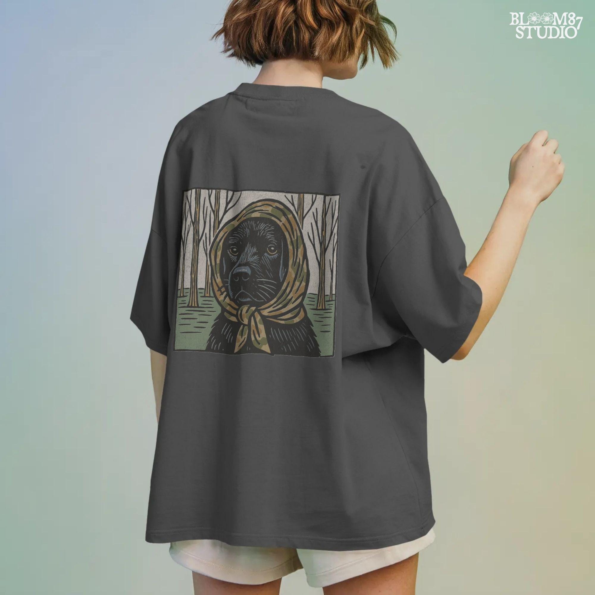 Digital PNG of a black labrador dog wearing a camo scarf in a forest setting, designed for hunting-themed sublimation printing