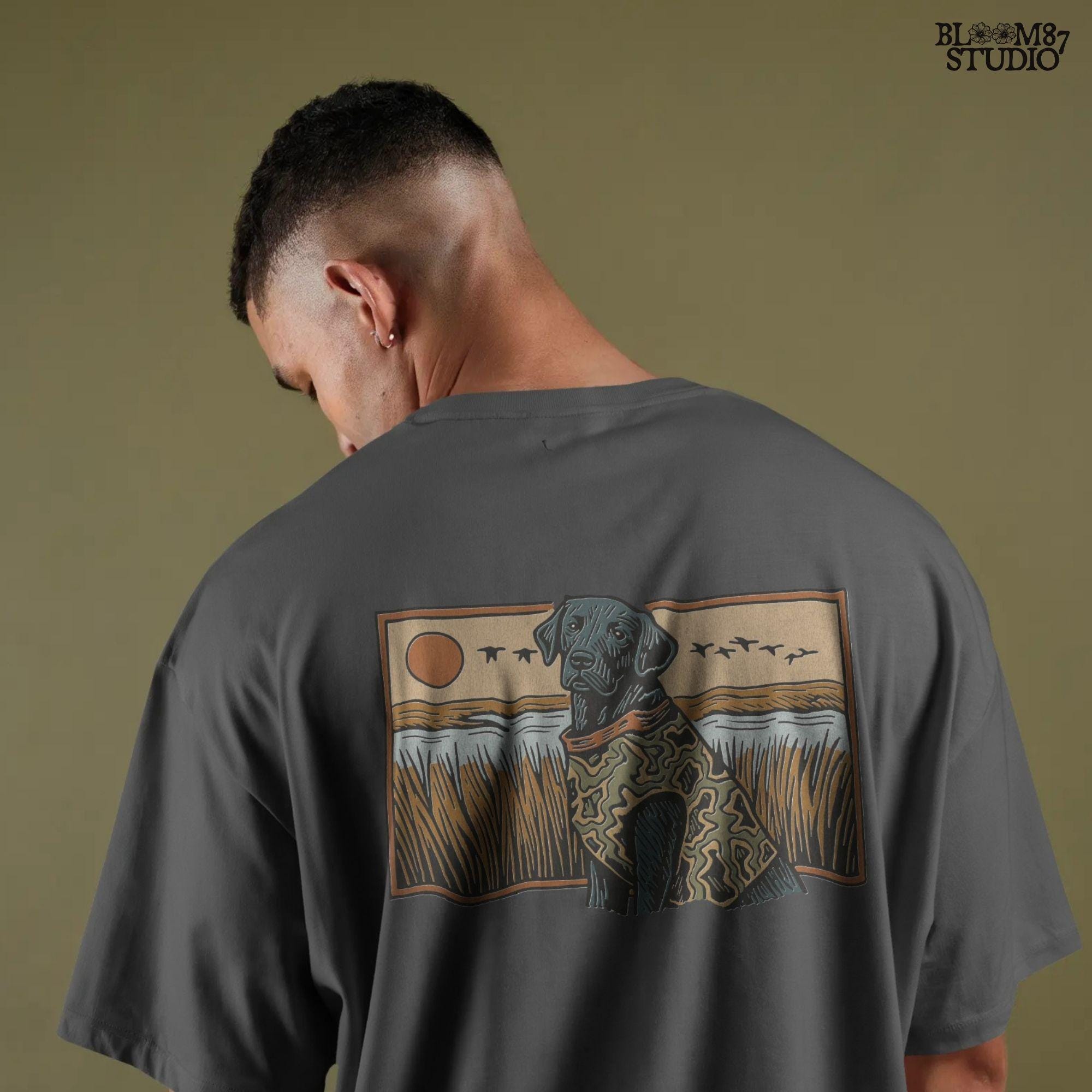 Camo-clad black Labrador retriever sitting in a grassy marsh with flying ducks and a sunset background, digital PNG for hunting dog sublimation designs.