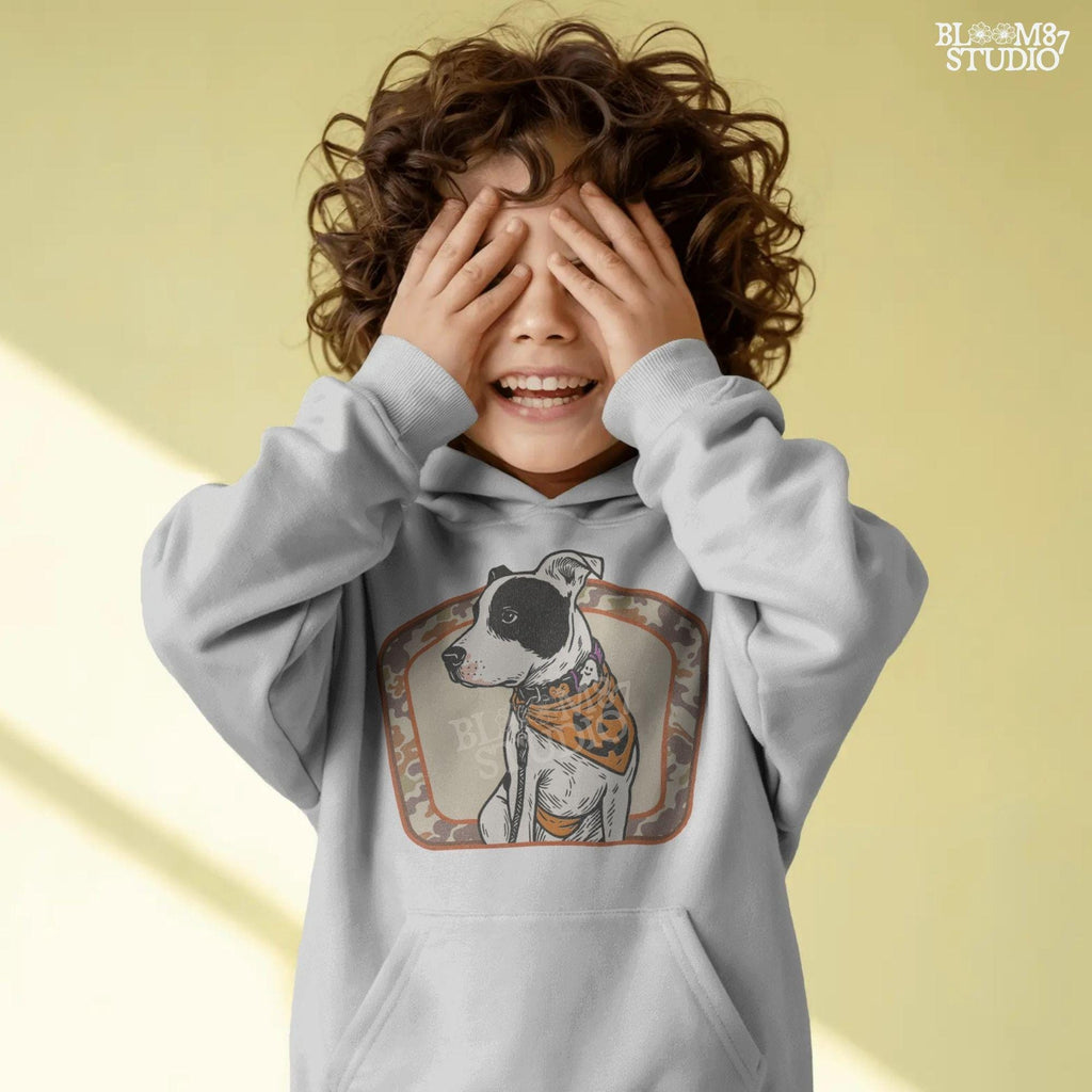 Illustration of a black and white pitbull wearing a jack-o’-lantern bandana and Halloween collar, framed by a camo background.