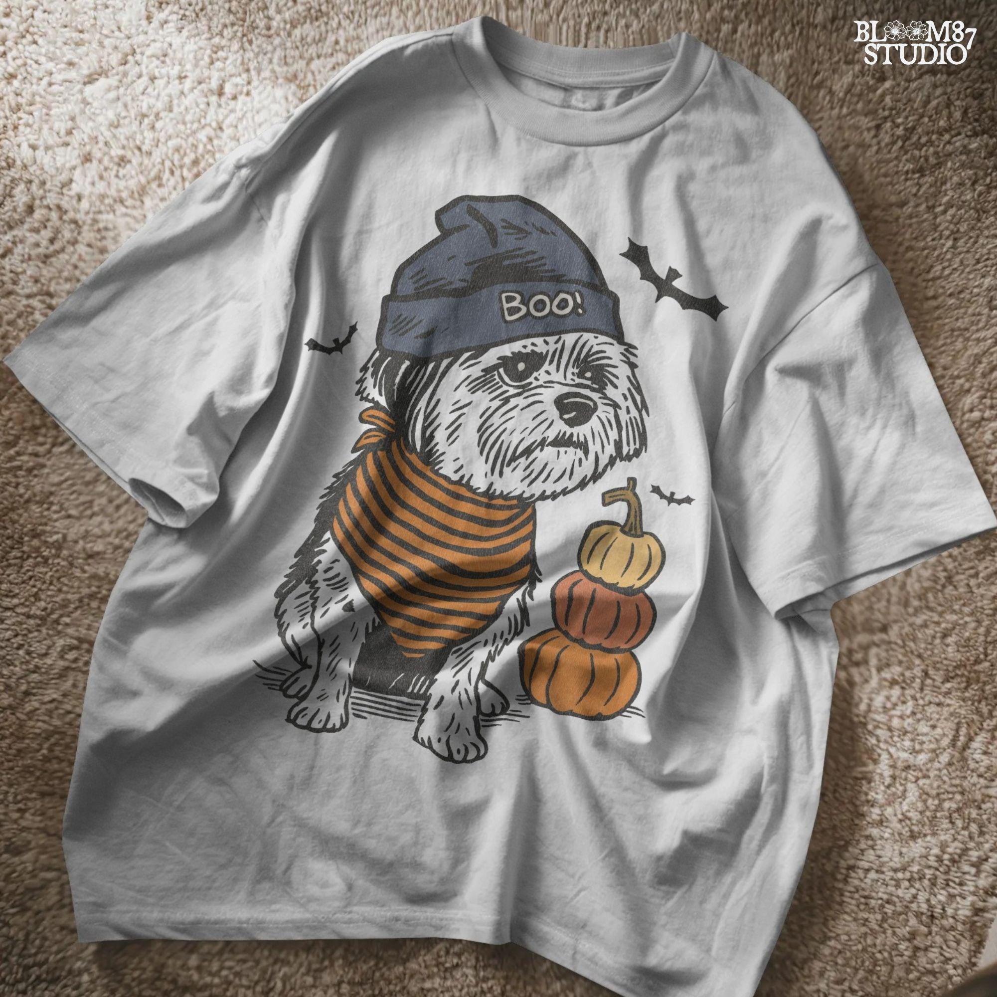 Illustration of a black dog wearing a “BOO!” hat and orange striped bandana, sitting next to stacked pumpkins on a Halloween background.