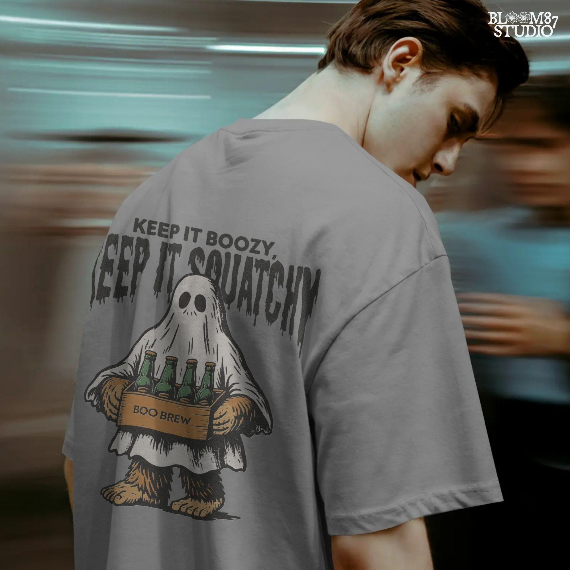 Funny Bigfoot dressed as a ghost holding a six-pack labeled “Boo Brew,” with spooky text “Keep It Boozy, Keep It Squatchy” above.