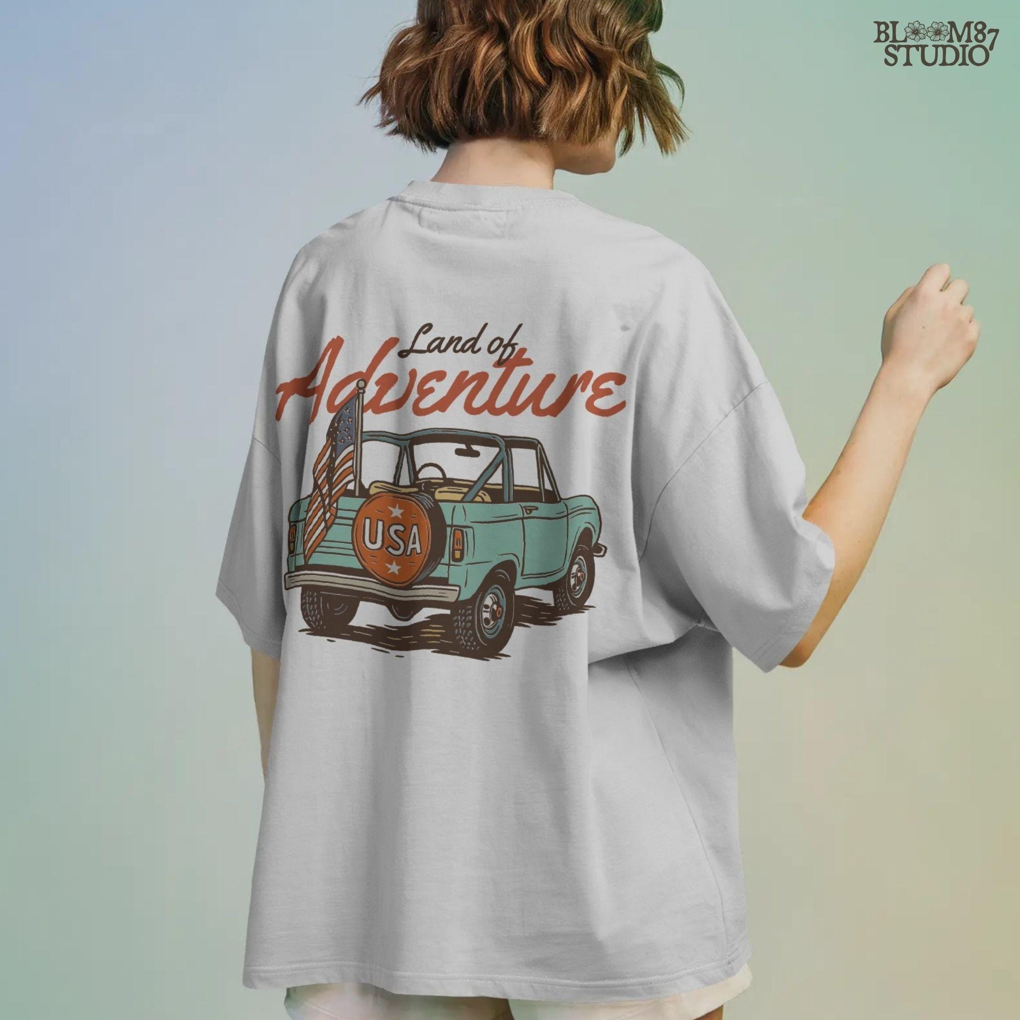 Vintage convertible truck with “USA” spare tire and American flag, text reads “Land of Adventure,” in a retro patriotic illustration style.