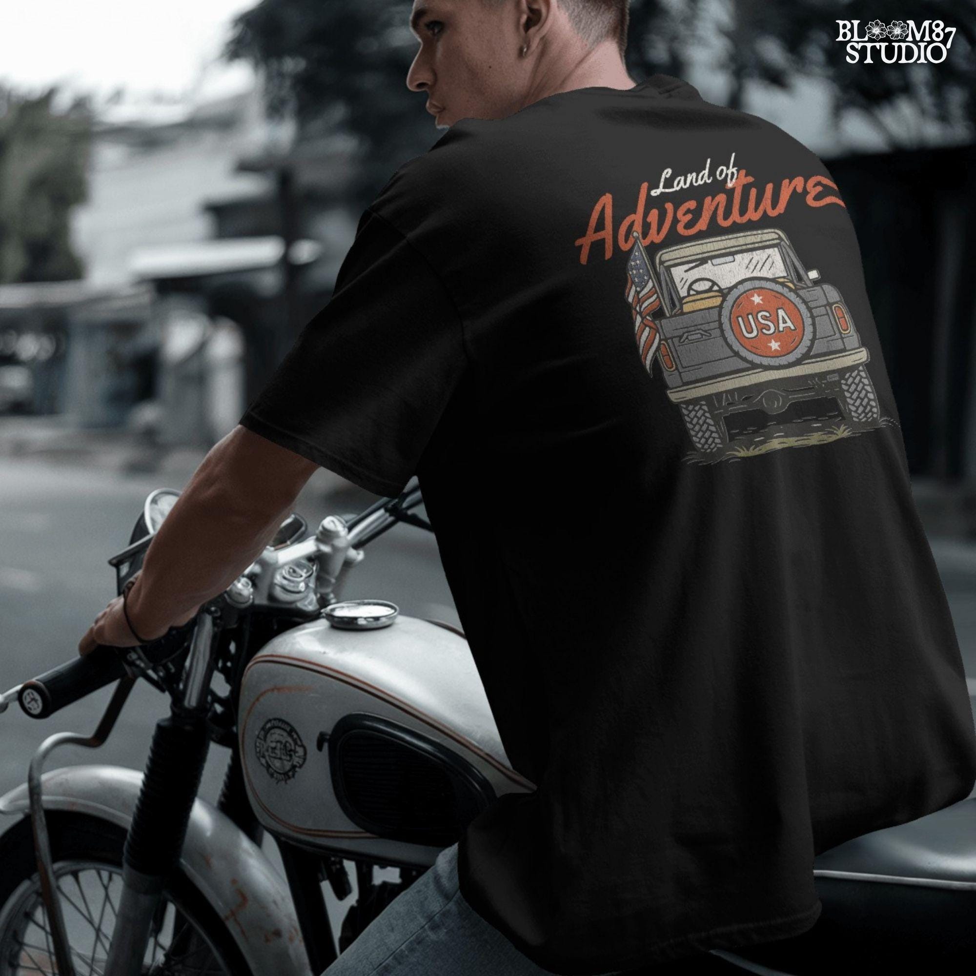 Vintage offroad truck seen from the back with “USA” spare tire and waving American flag, text reads “Land of Adventure” in retro patriotic style.