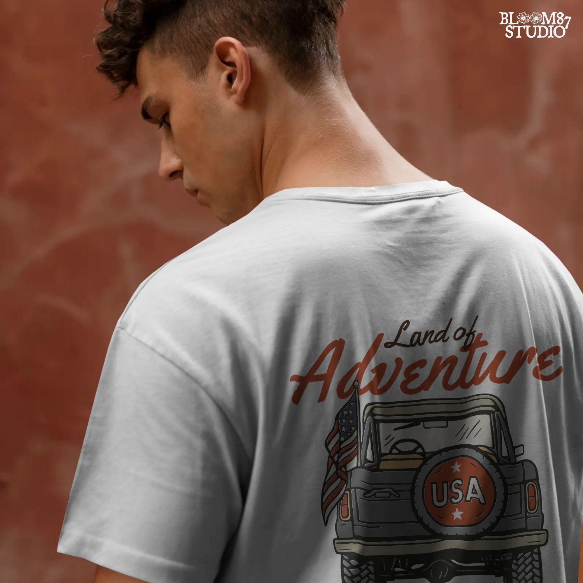 Vintage offroad truck seen from the back with “USA” spare tire and waving American flag, text reads “Land of Adventure” in retro patriotic style.