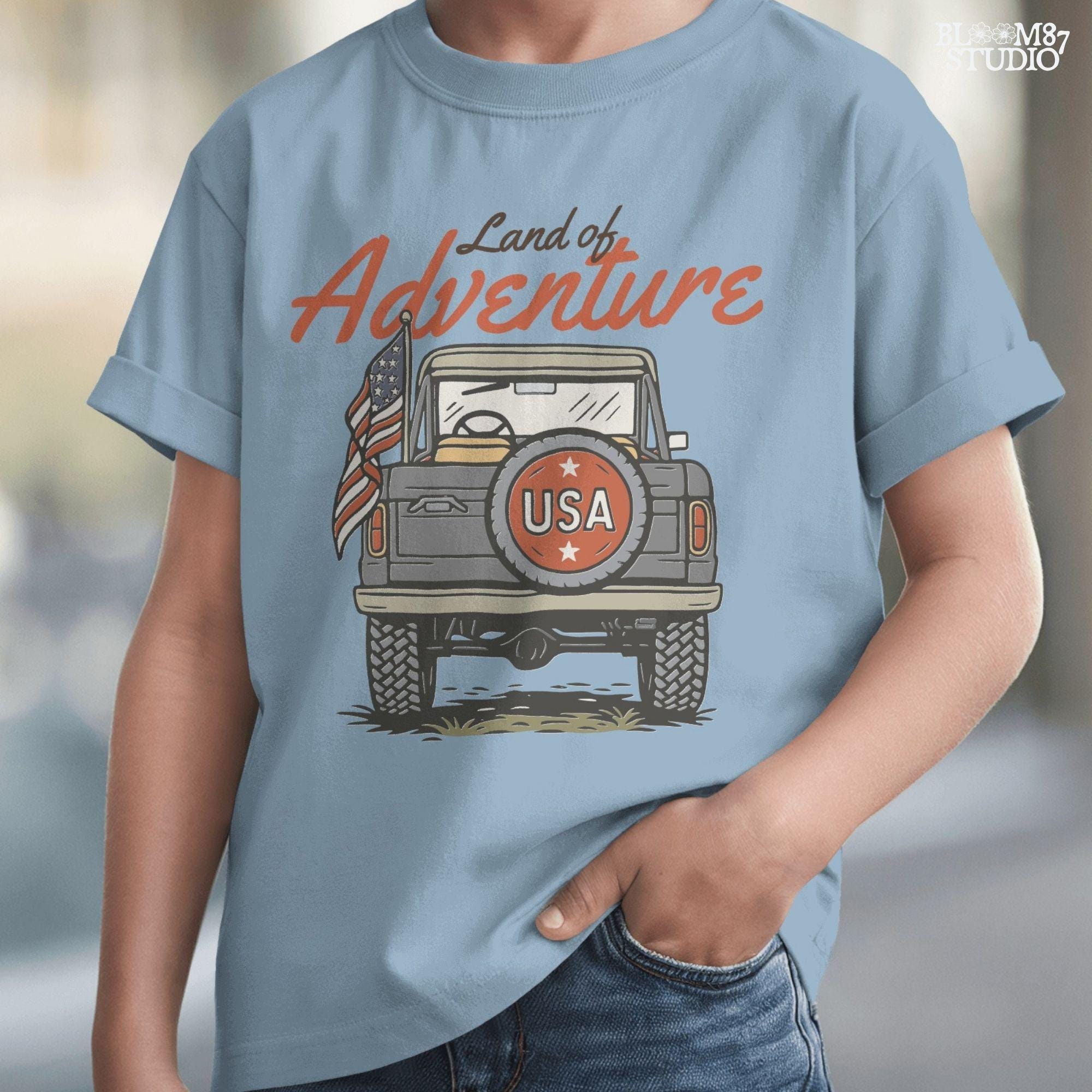 Vintage offroad truck seen from the back with “USA” spare tire and waving American flag, text reads “Land of Adventure” in retro patriotic style.