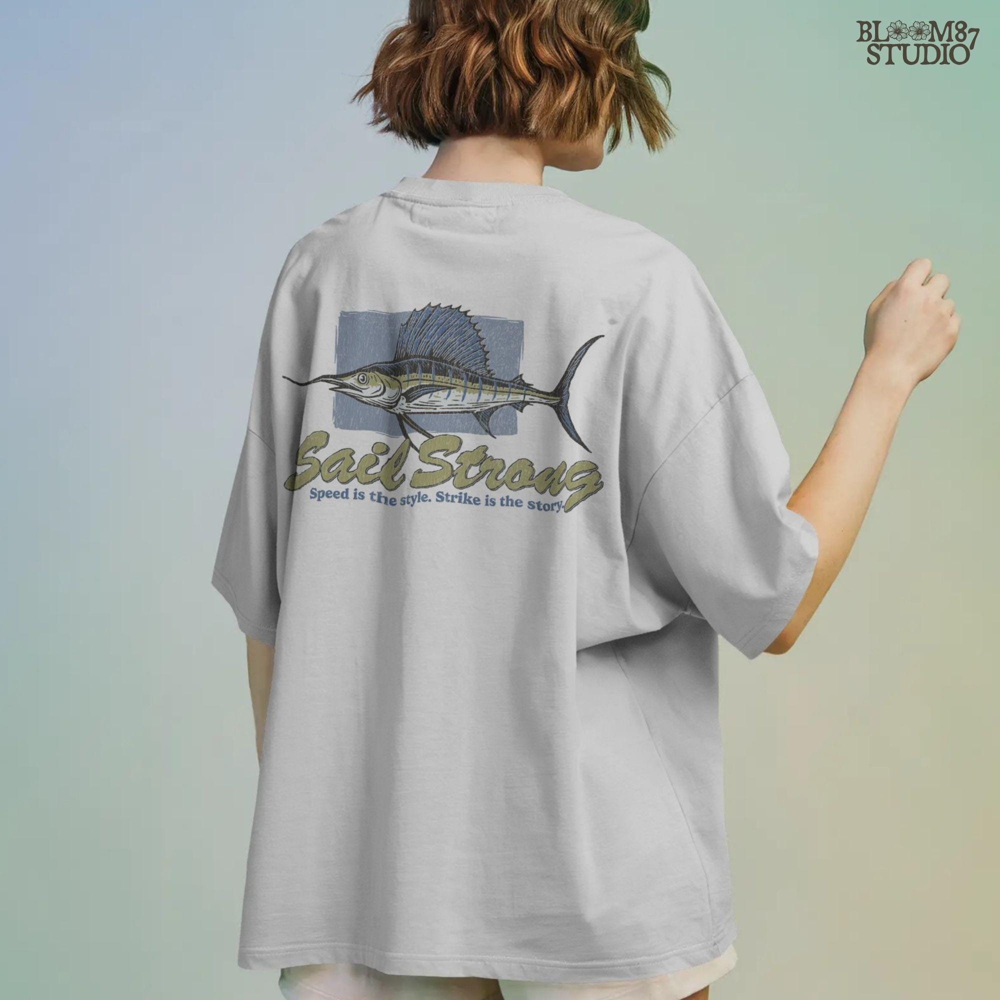 Illustrated sailfish with bold dorsal fin and text “Sail Strong – Speed is the style. Strike is the story” in nautical, vintage style.