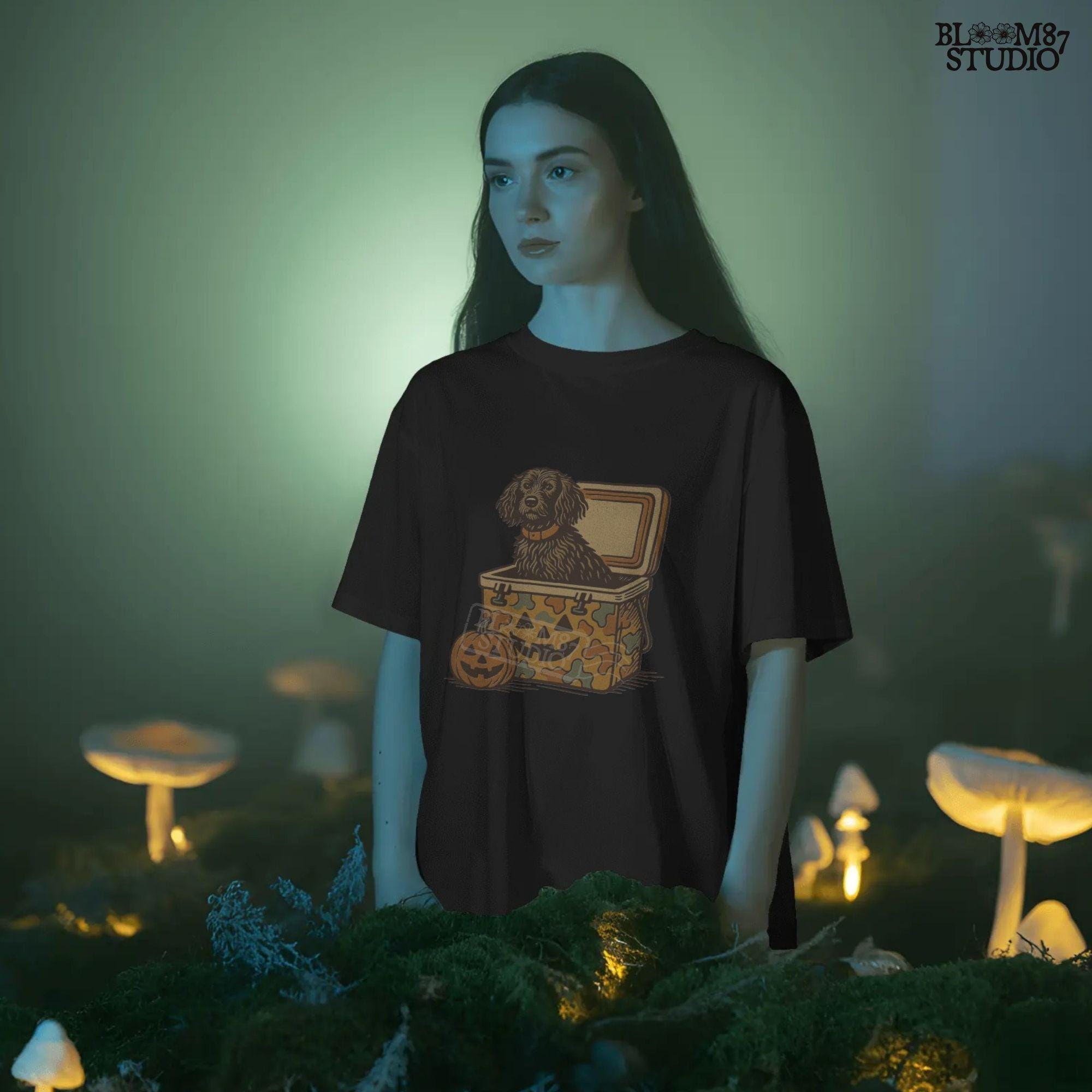 Halloween-themed PNG of a fluffy dog sitting inside a pumpkin-faced camouflage cooler, with jack-o’-lantern pumpkins next to it.