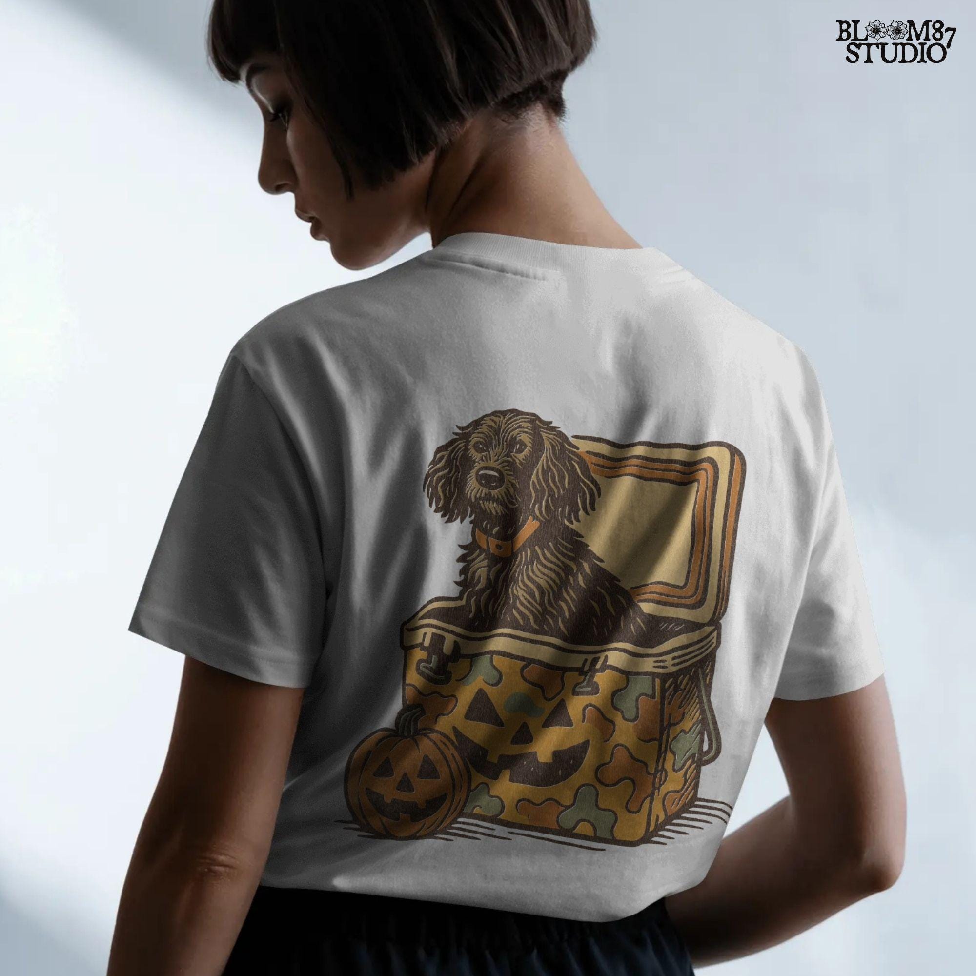 Halloween-themed PNG of a fluffy dog sitting inside a pumpkin-faced camouflage cooler, with jack-o’-lantern pumpkins next to it.