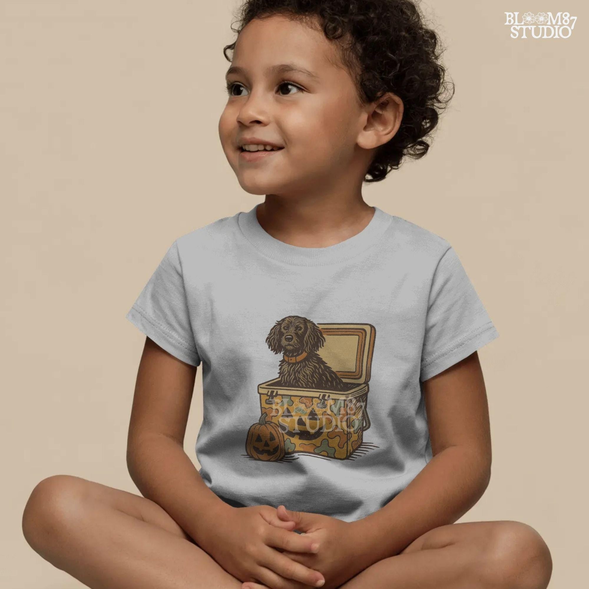 Halloween-themed PNG of a fluffy dog sitting inside a pumpkin-faced camouflage cooler, with jack-o’-lantern pumpkins next to it.