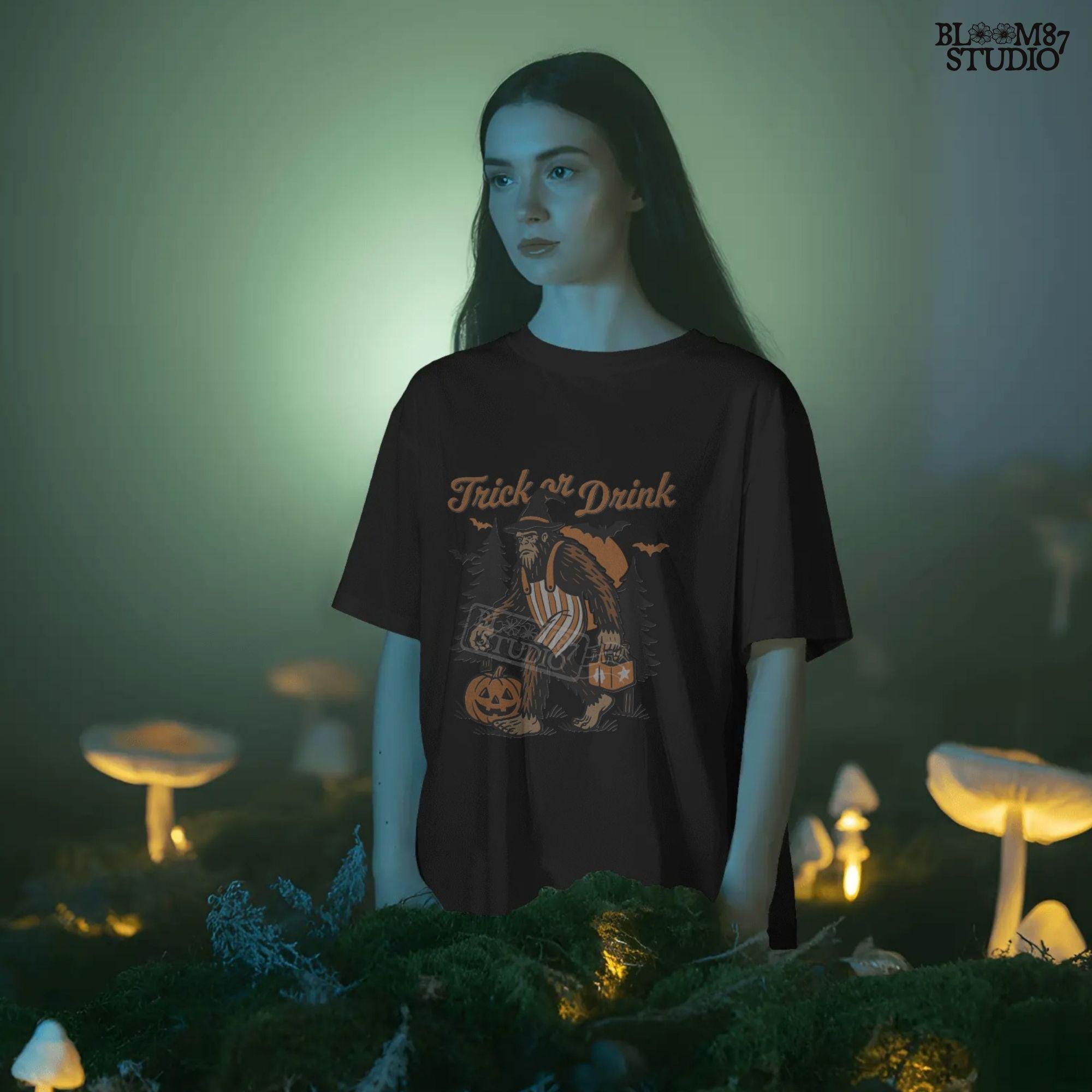 Funny Halloween bigfoot holding beer in witch hat and striped overalls, walking past pumpkins and trees with “Trick or Drink” text above.