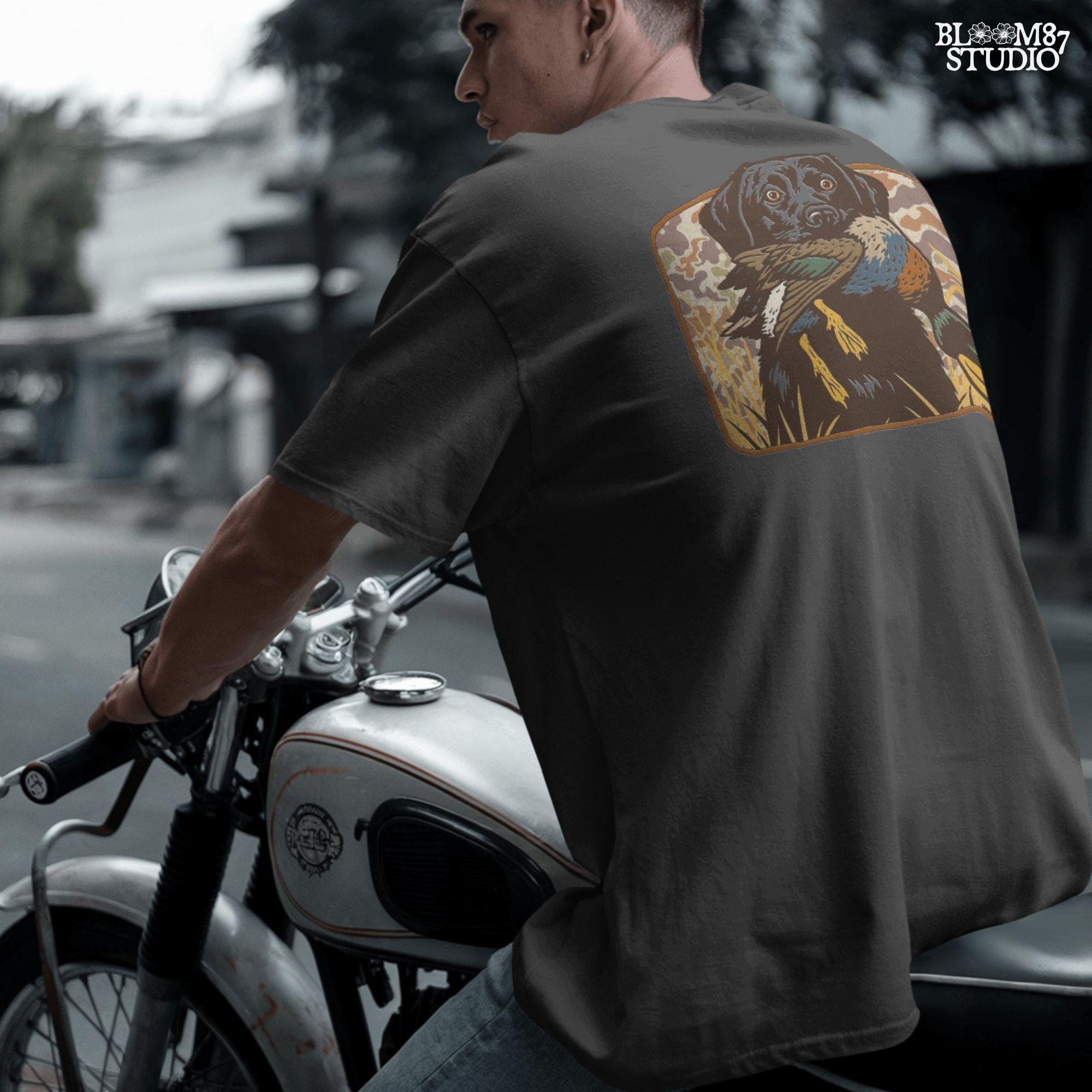 Vintage-style illustration of a black Labrador retriever holding a mallard duck in its mouth with a camouflage background, ideal for duck hunting designs.