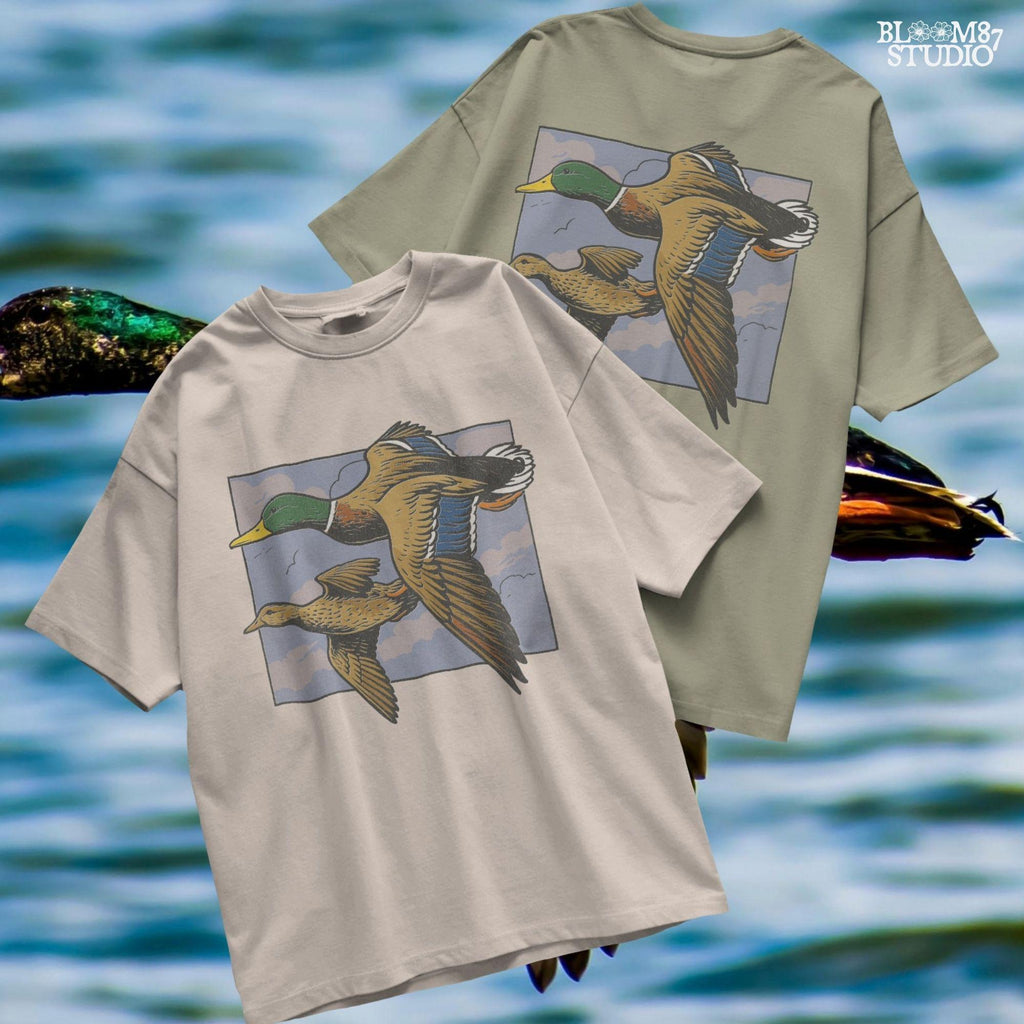 Vintage-style illustration of a flying mallard duck pair in mid-air with a cloudy sky background, ideal for rustic hunting or nature-themed designs.