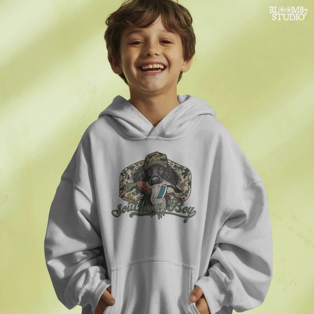 Illustration of a black hunting dog wearing a camo hat, holding a mallard duck in its mouth with the text “Southern Boy” below, in a rustic Southern style.