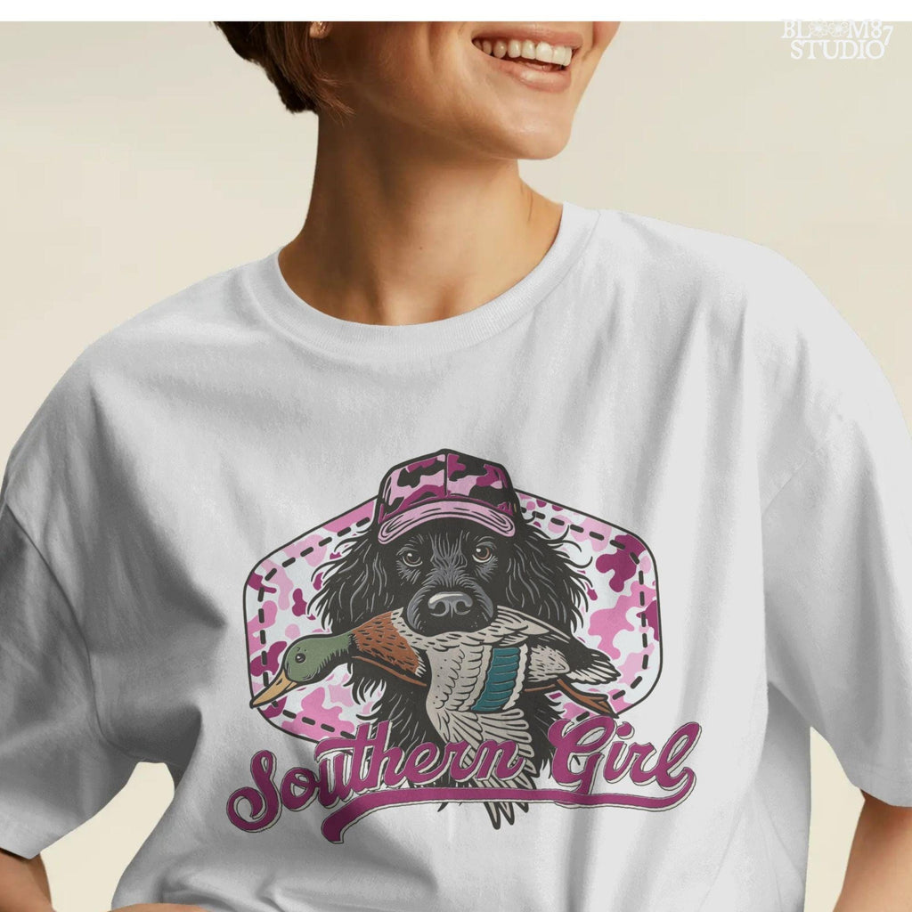 Illustration of a black hunting dog wearing a pink camo hat and holding a mallard duck, with “Southern Girl” text and pink camouflage background.