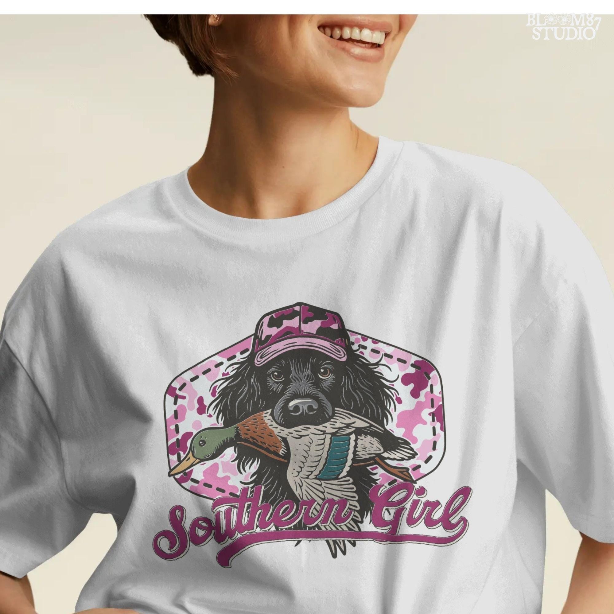 Illustration of a black hunting dog wearing a pink camo hat and holding a mallard duck, with “Southern Girl” text and pink camouflage background.