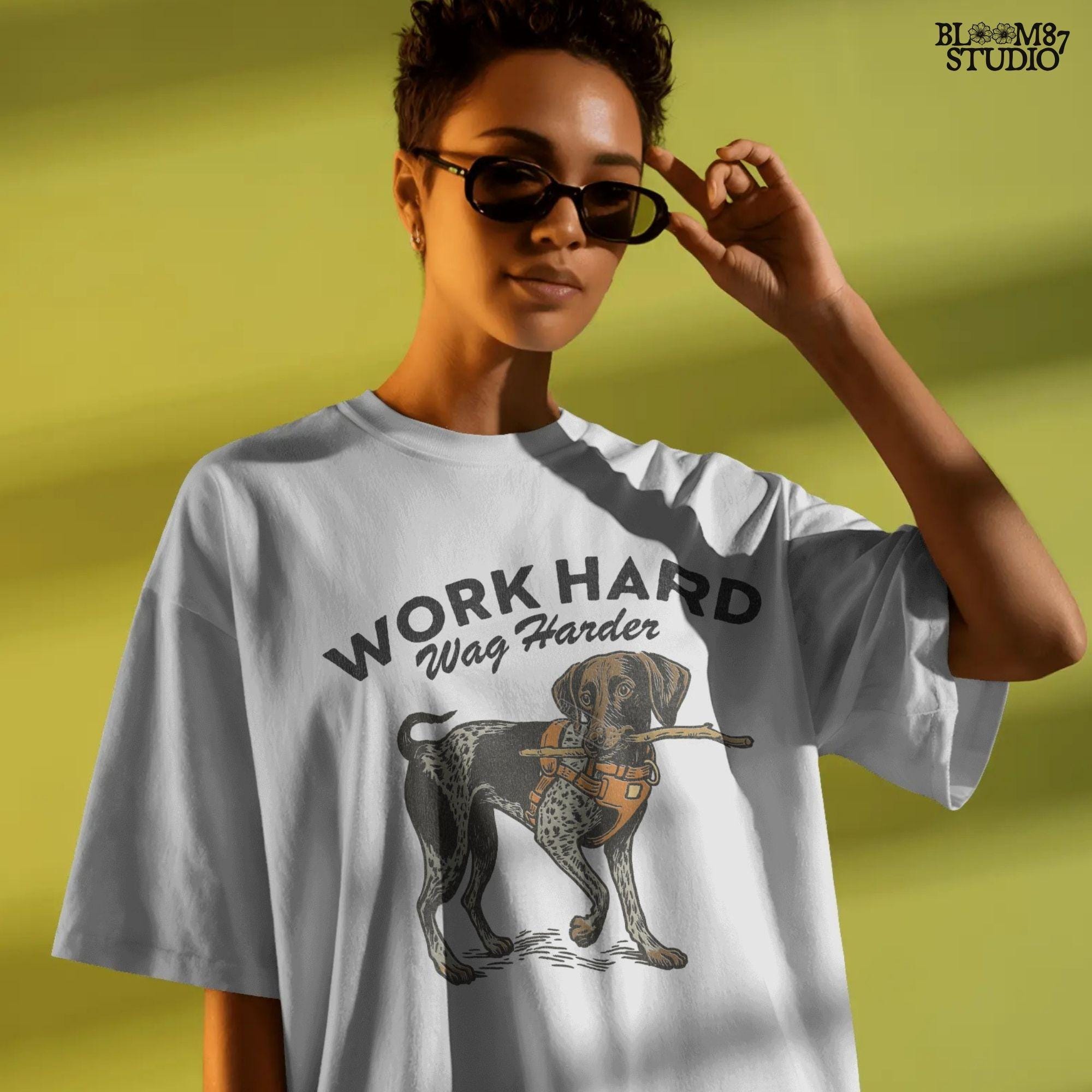 German Shorthaired Pointer dog wearing orange harness holding a stick with text “Work Hard Wag Harder” above, PNG design for sublimation use