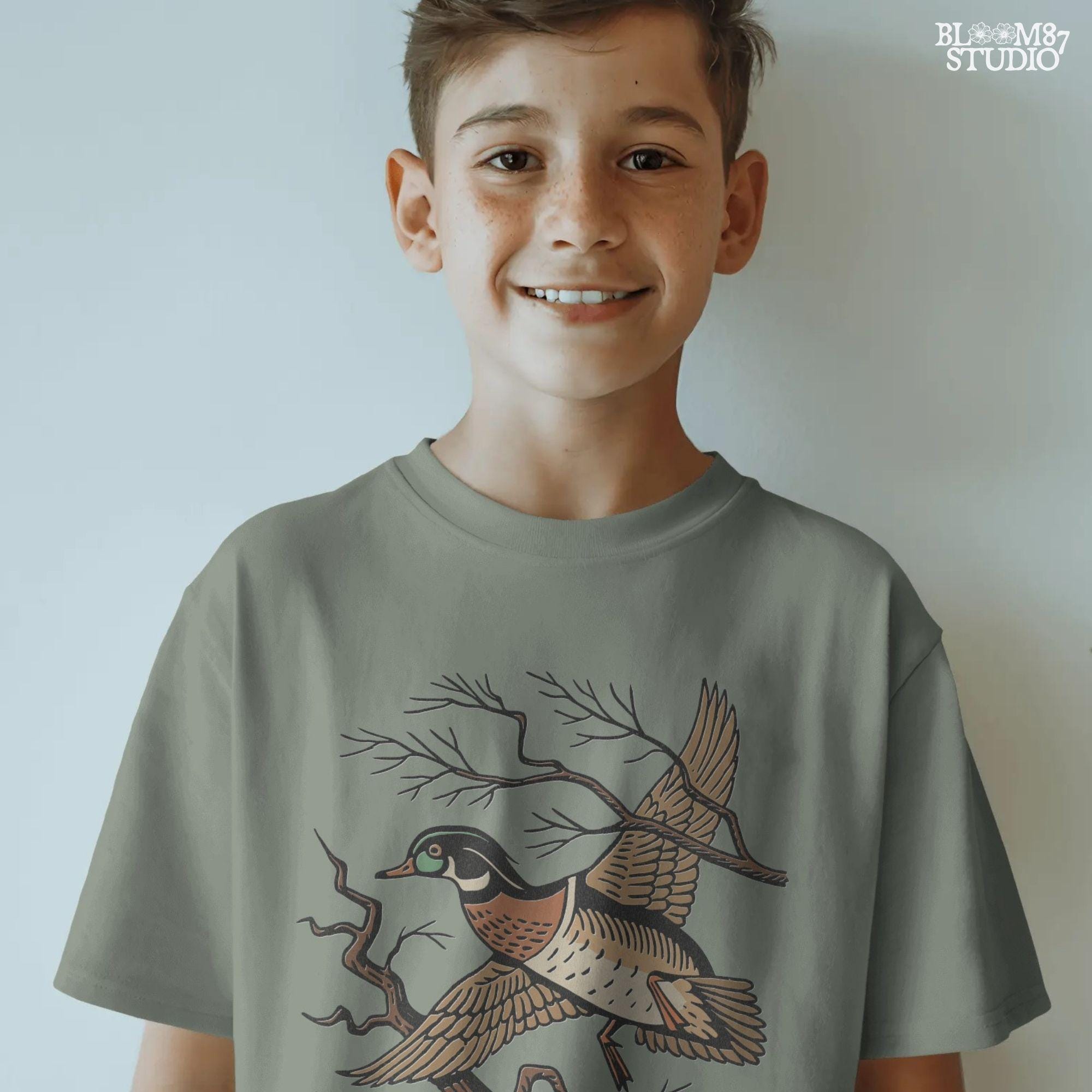 Vintage wood duck flying over bare branches with “Woodland Chase” text in rustic orange and black; sublimation PNG for hunting or fall apparel.