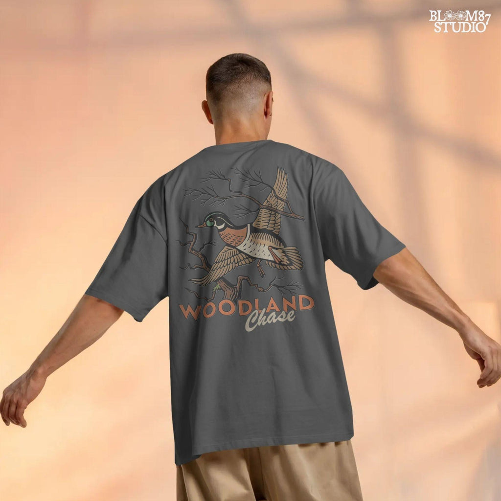 Vintage wood duck flying over bare branches with “Woodland Chase” text in rustic orange and black; sublimation PNG for hunting or fall apparel.