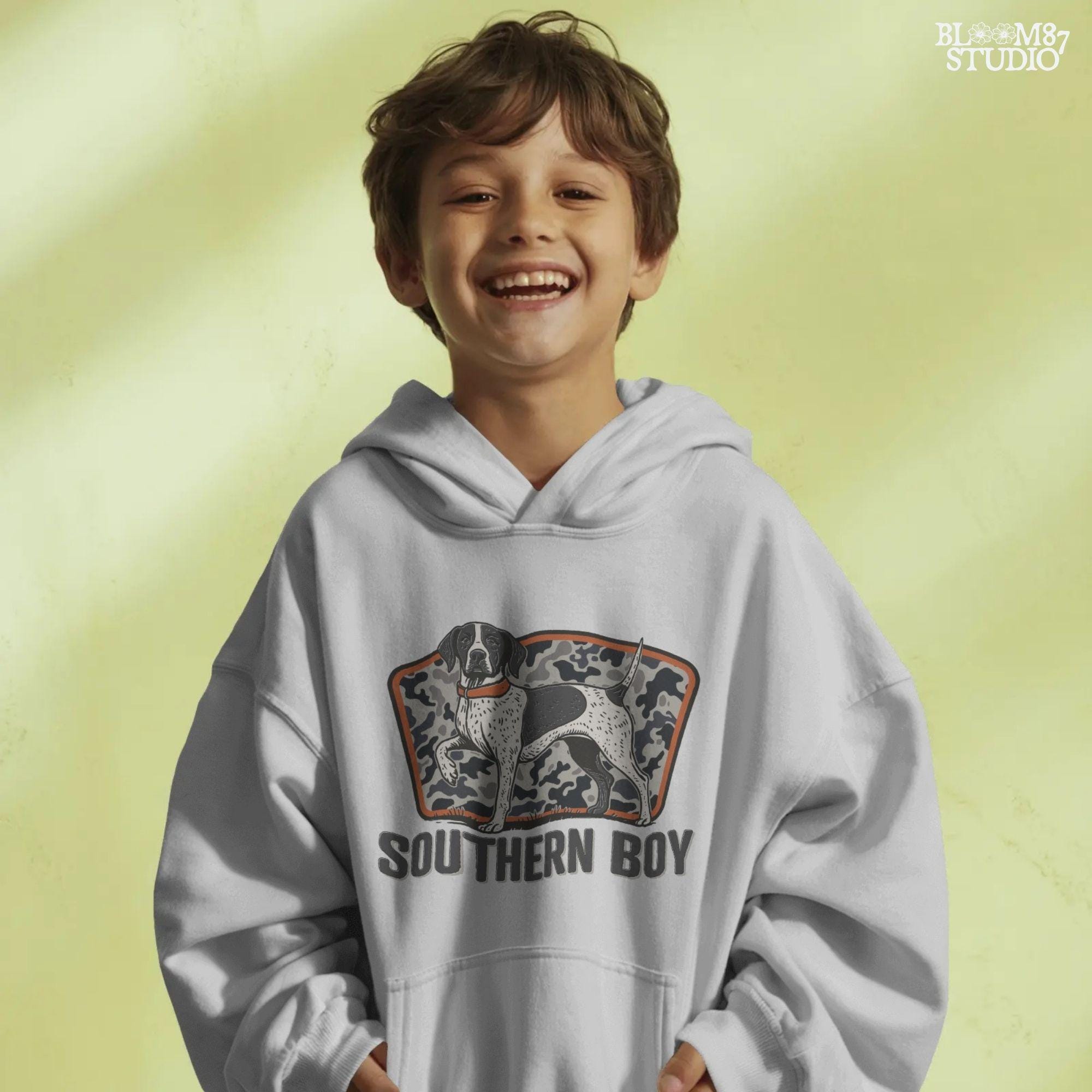 Illustration of a black and white pointer hunting dog standing in front of a gray camo background with the words “Southern Boy” beneath in bold rustic font.