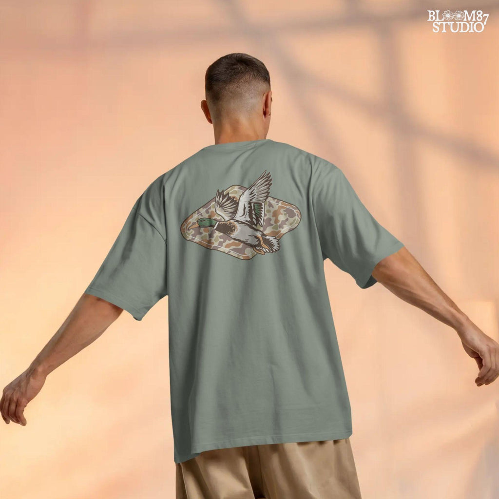 Mallard duck flying over a tan and brown woodland camo background, stylized for fall hunting and Thanksgiving sublimation projects.
