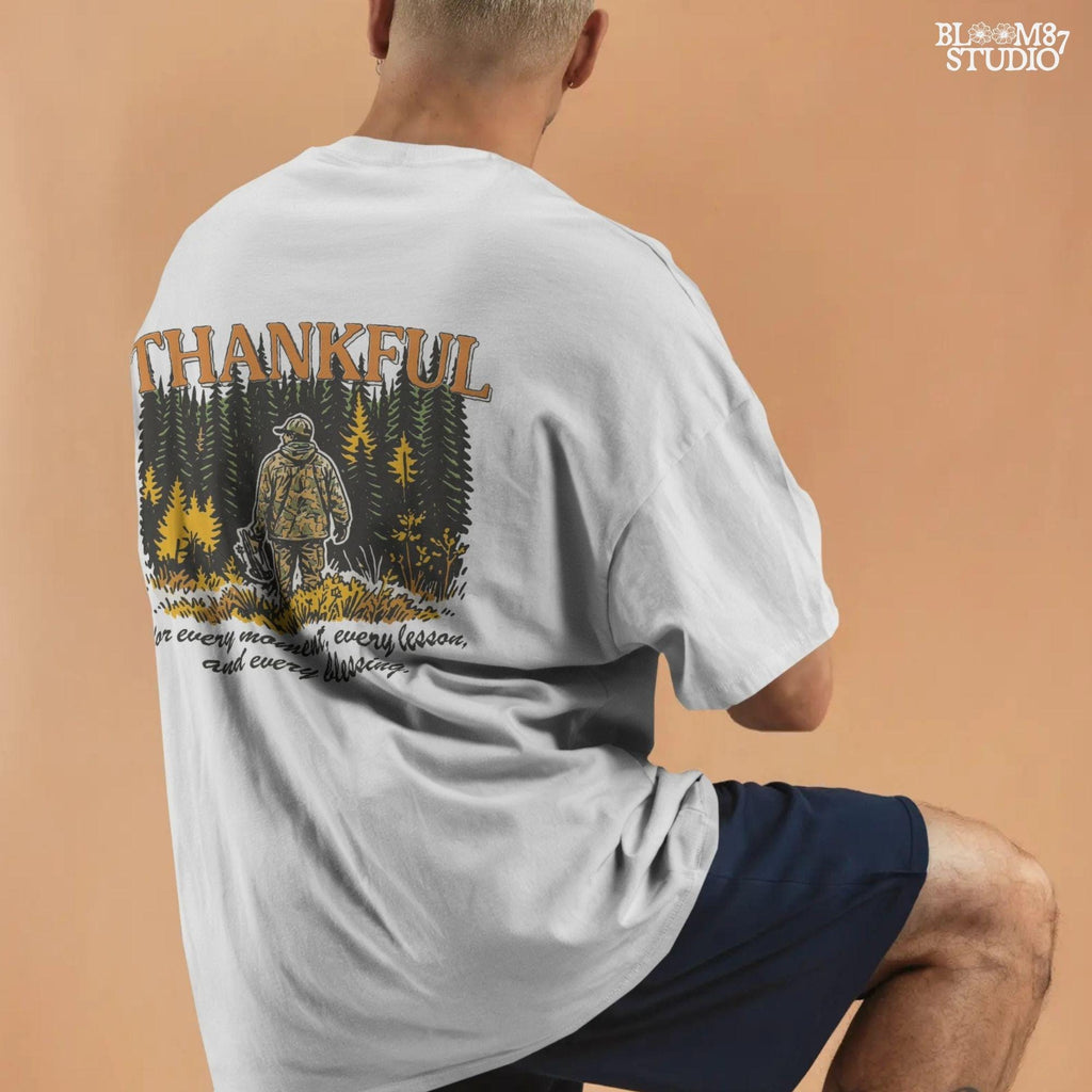 Illustration of a hunter in camo standing in a fall forest with the word “THANKFUL” above and a quote below, designed for sublimation projects.