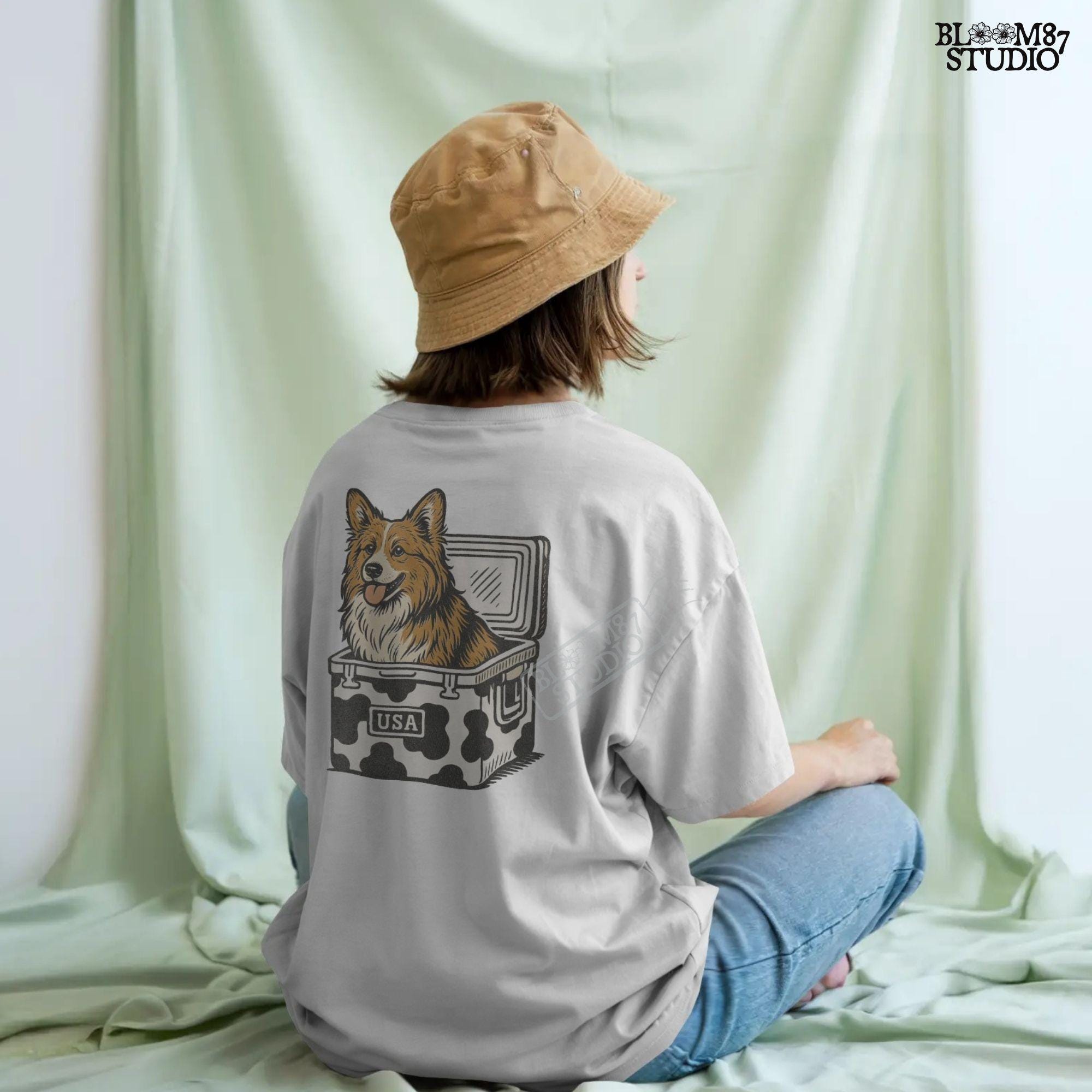 Corgi sitting inside a cow print cooler labeled “USA”, rustic cartoon-style digital PNG for patriotic pet sublimation and country-themed designs