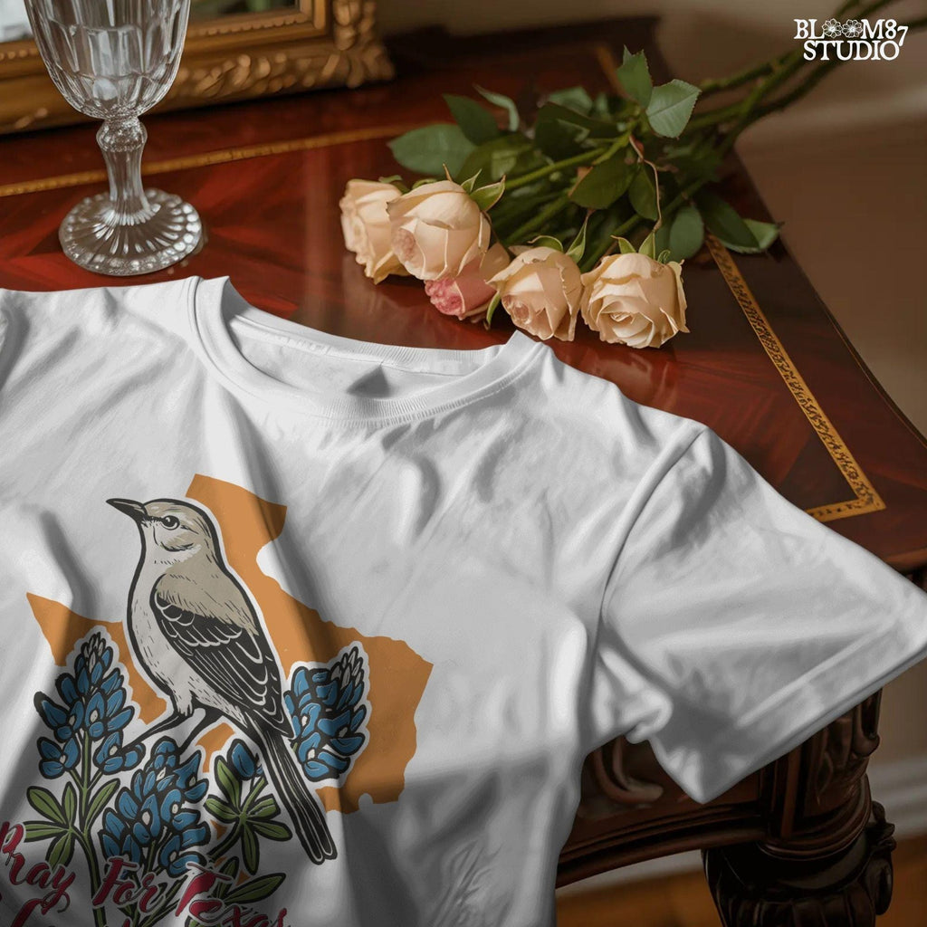 Illustration of a mockingbird on bluebonnets in front of Texas state outline with text “Pray for Texas Hill Country Strong,” designed for sublimation and awareness.