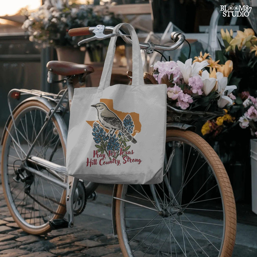 Illustration of a mockingbird on bluebonnets in front of Texas state outline with text “Pray for Texas Hill Country Strong,” designed for sublimation and awareness.
