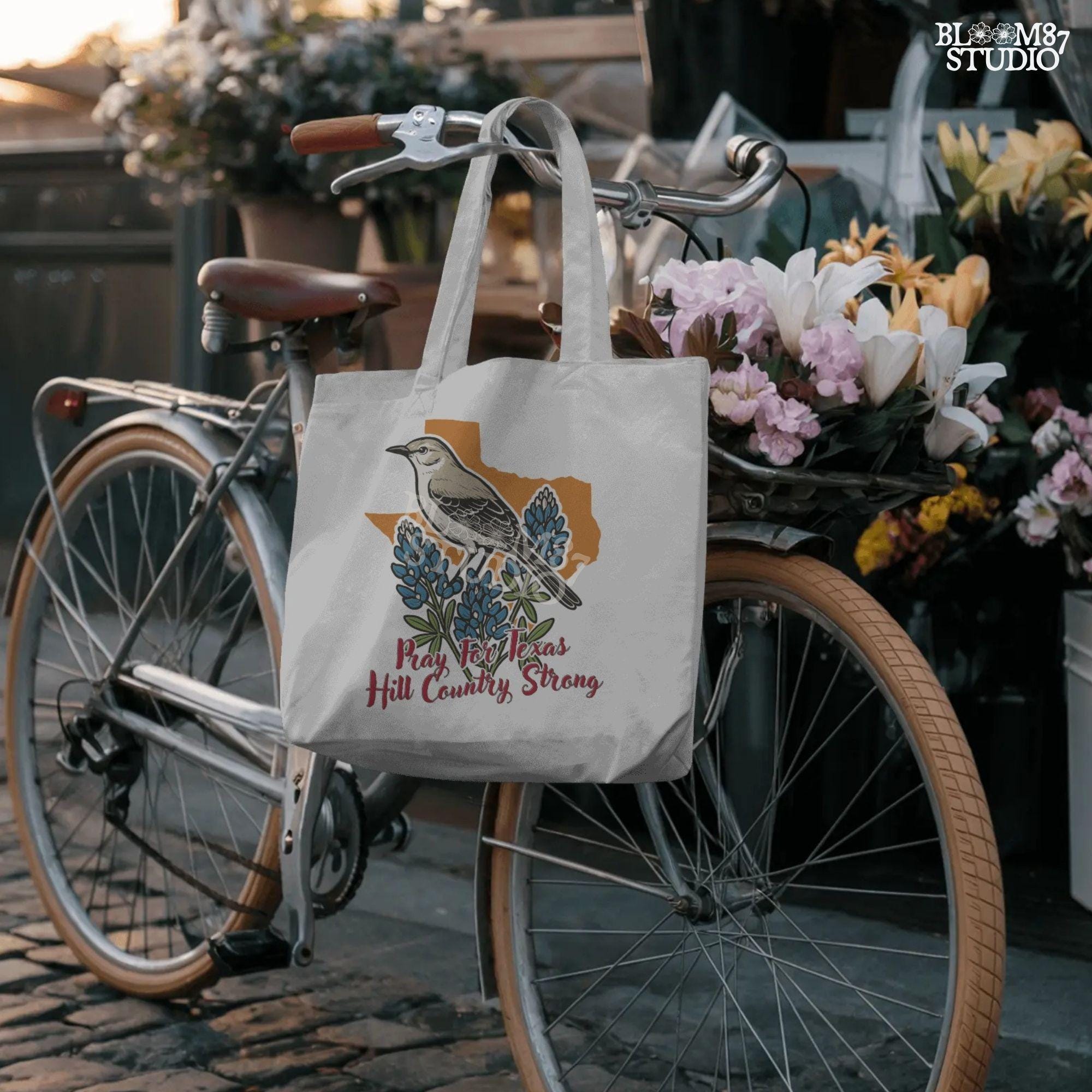 Illustration of a mockingbird on bluebonnets in front of Texas state outline with text “Pray for Texas Hill Country Strong,” designed for sublimation and awareness.