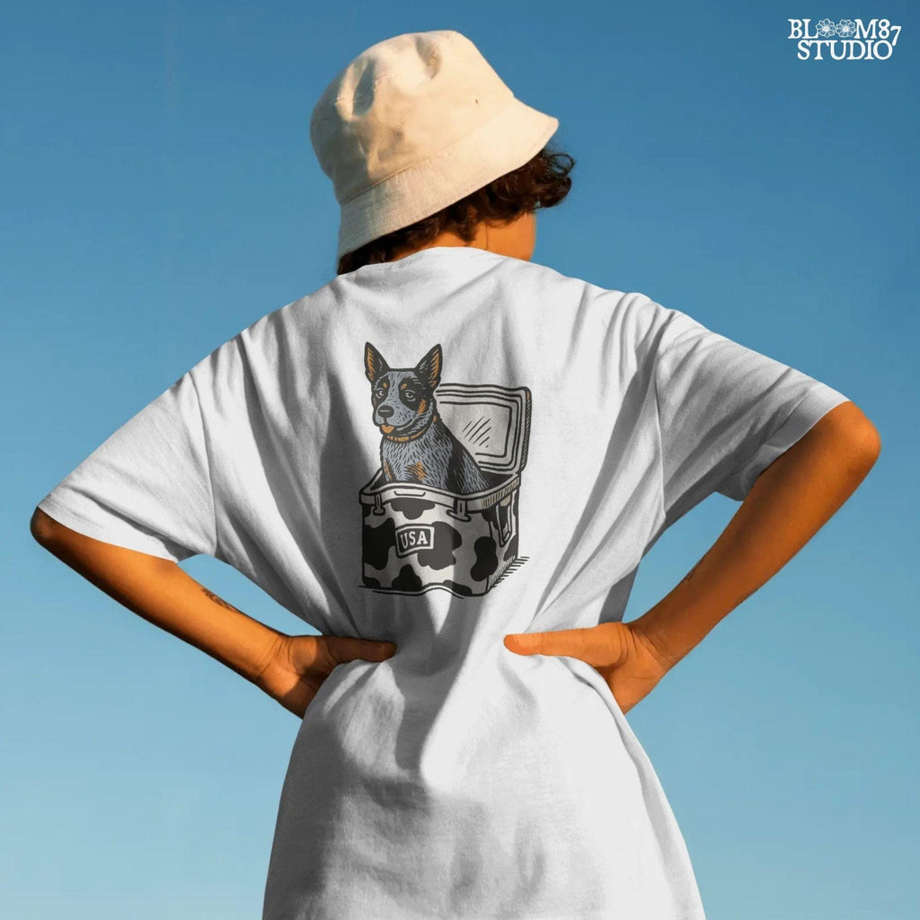 Cartoon-style Blue Heeler dog sitting inside a cowprint cooler with USA patch, perfect for southern patriotic summer sublimation design.