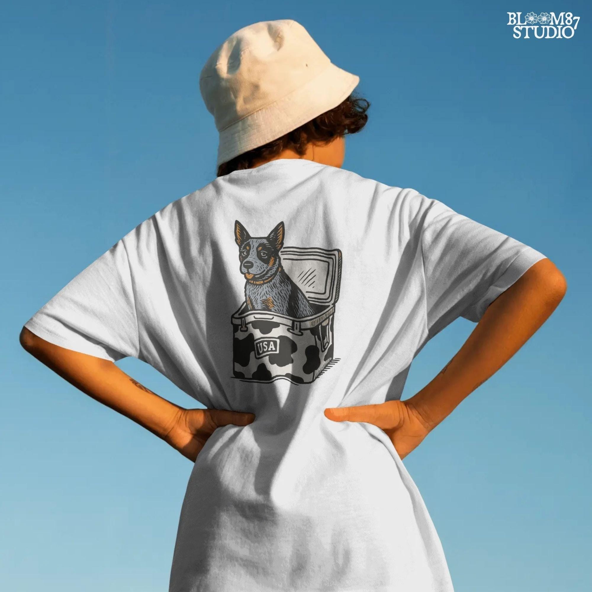 Cartoon-style Blue Heeler dog sitting inside a cowprint cooler with USA patch, perfect for southern patriotic summer sublimation design.