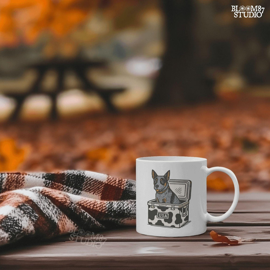 Cartoon-style Blue Heeler dog sitting inside a cowprint cooler with USA patch, perfect for southern patriotic summer sublimation design.