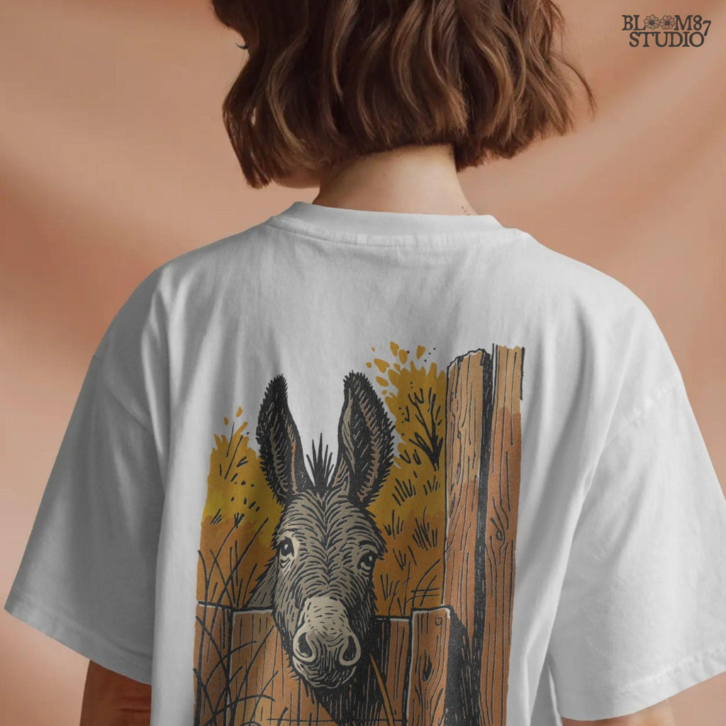 Vintage-style donkey looking through a rustic wooden fence with golden fall foliage in the background, perfect for sublimation crafts