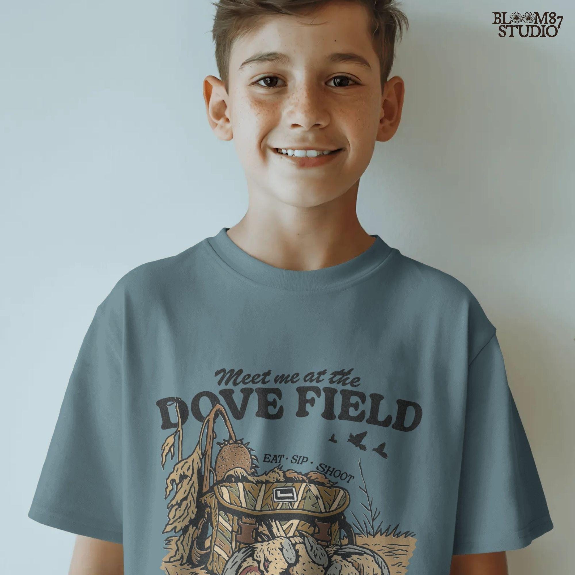 Camo hunting bag in a cornfield surrounded by harvested mourning doves with the phrase “Meet Me at the Dove Field” in vintage lettering.